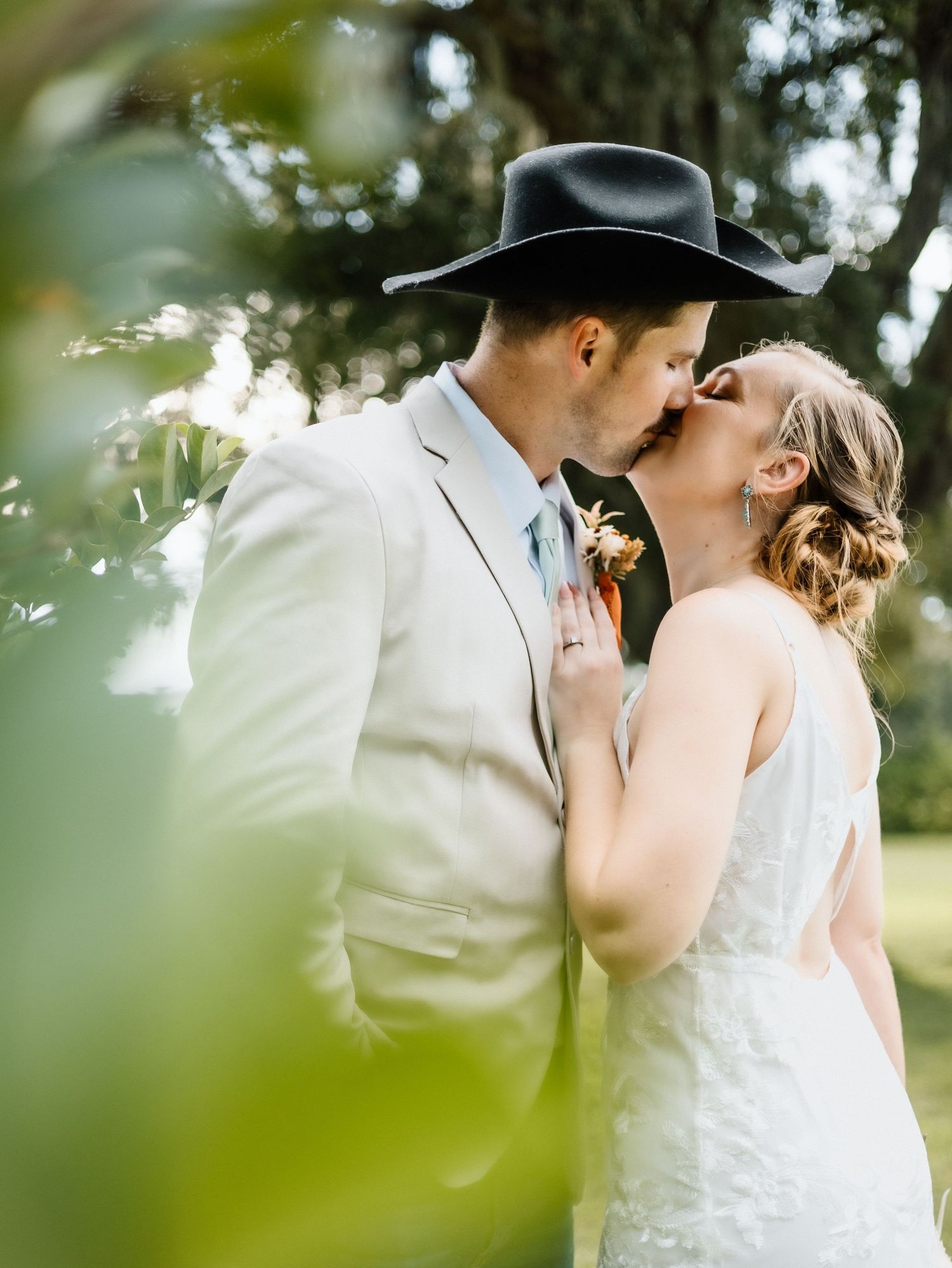 A romantic kiss between newlyweds in a dreamy outdoor garden setting with soft natural light.