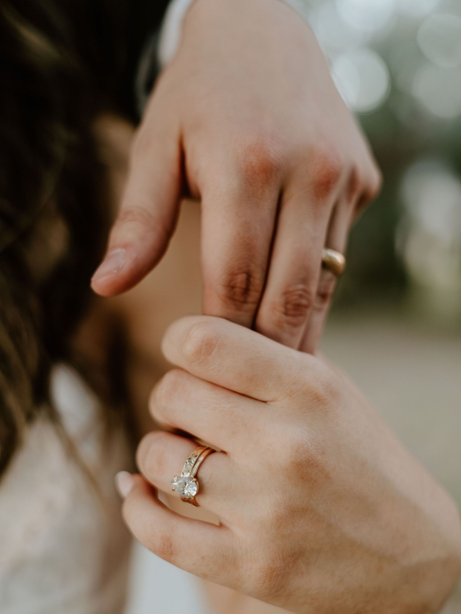 Close-up shot of hands displaying an elegant diamond engagement ring.