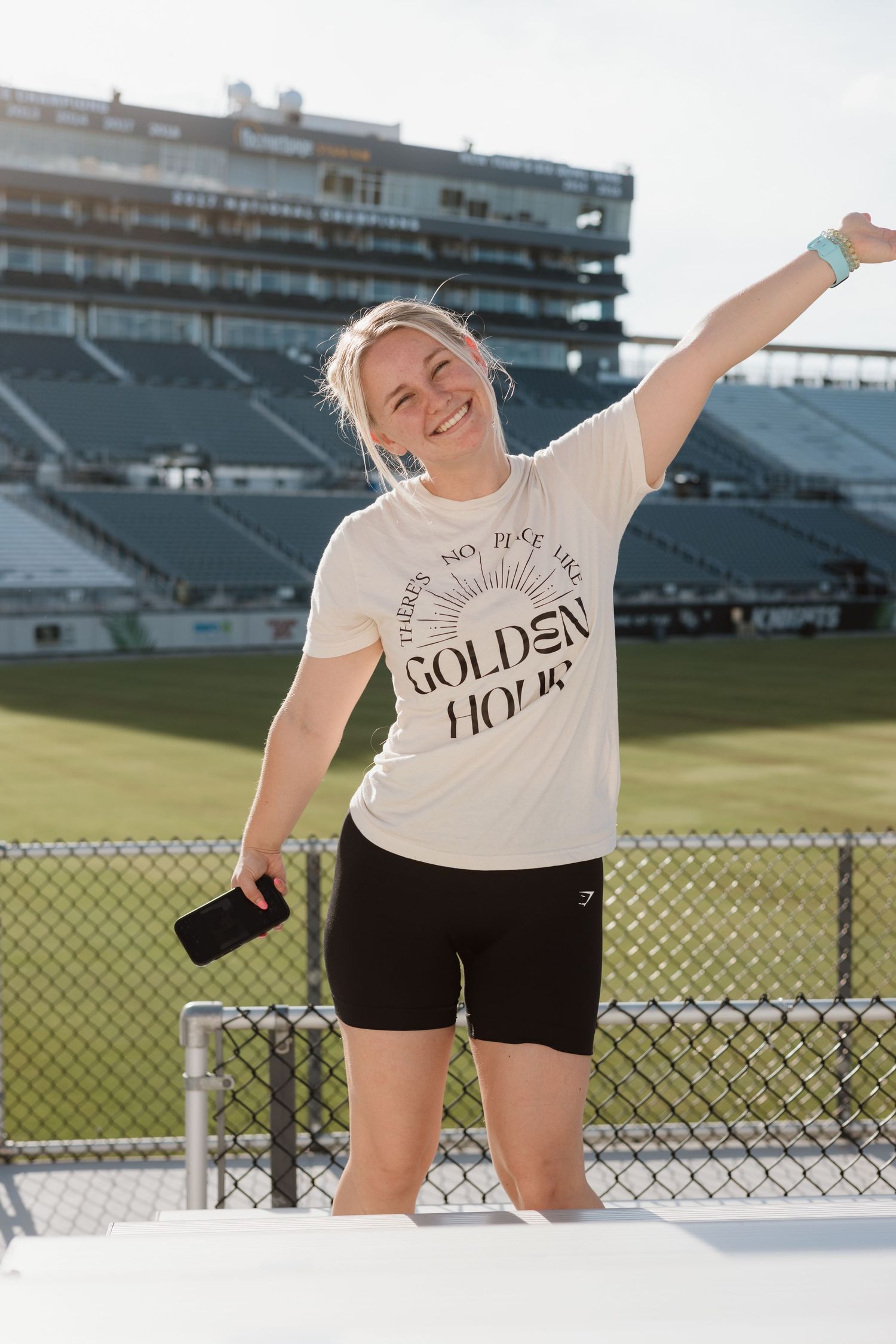 Cheerful poses on a sports field with stadium seats visible in the background.