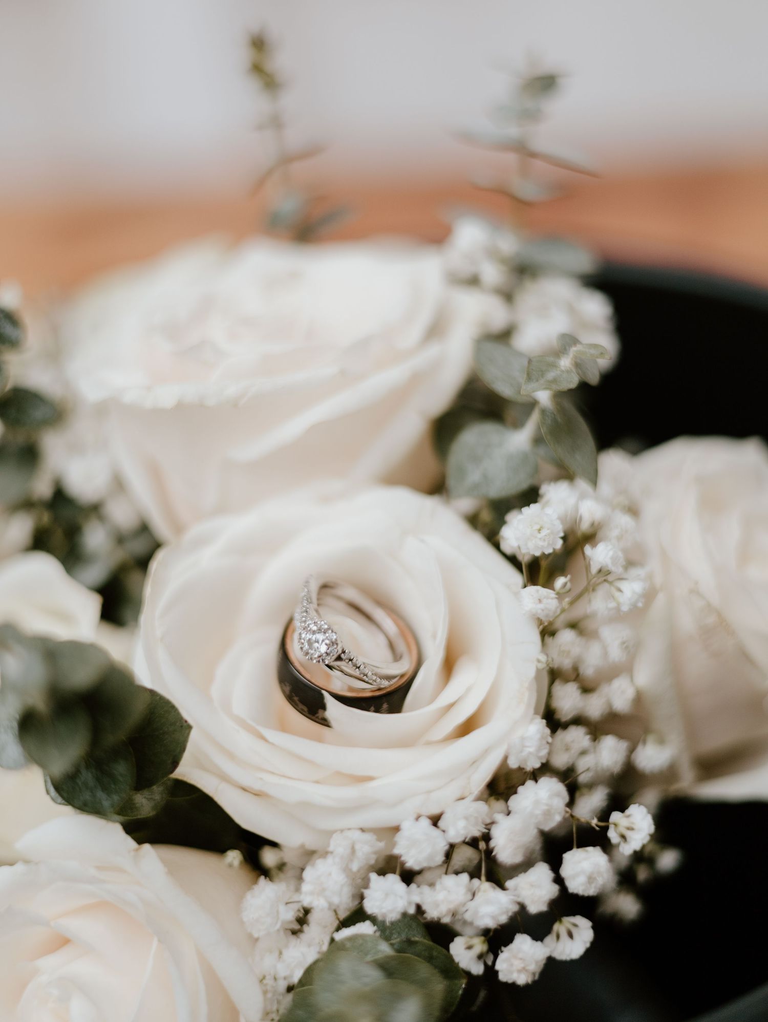 Wedding ring nestled in a white rose with baby's breath and greenery.