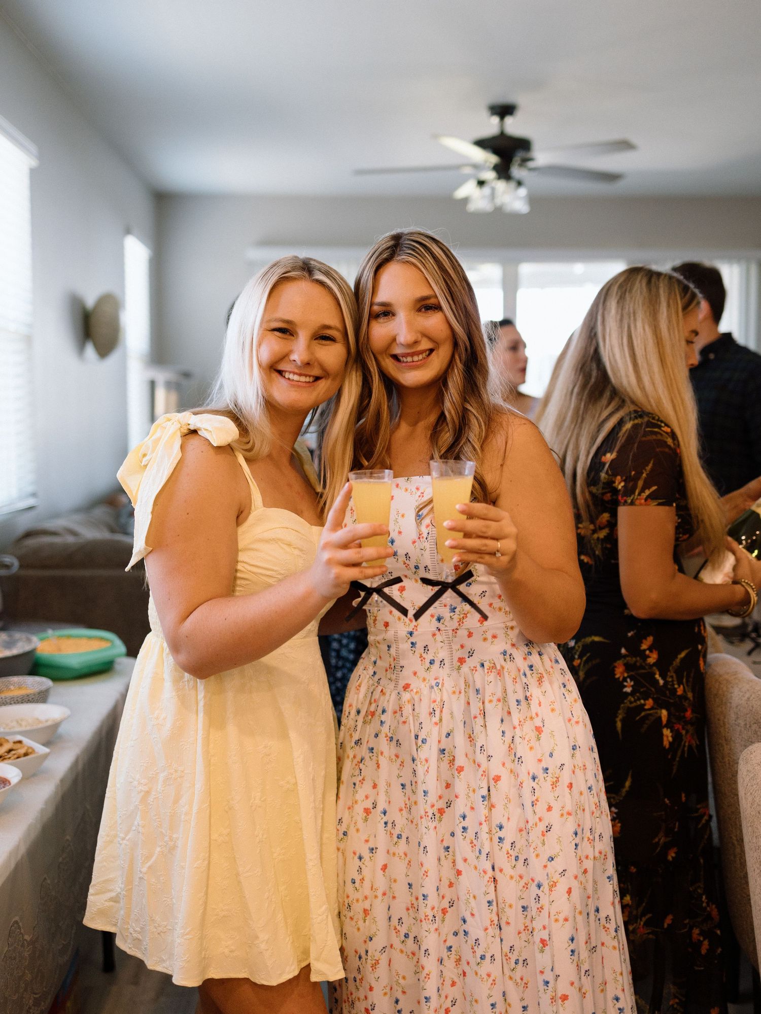 Friends celebrating in summer dresses at an indoor gathering.