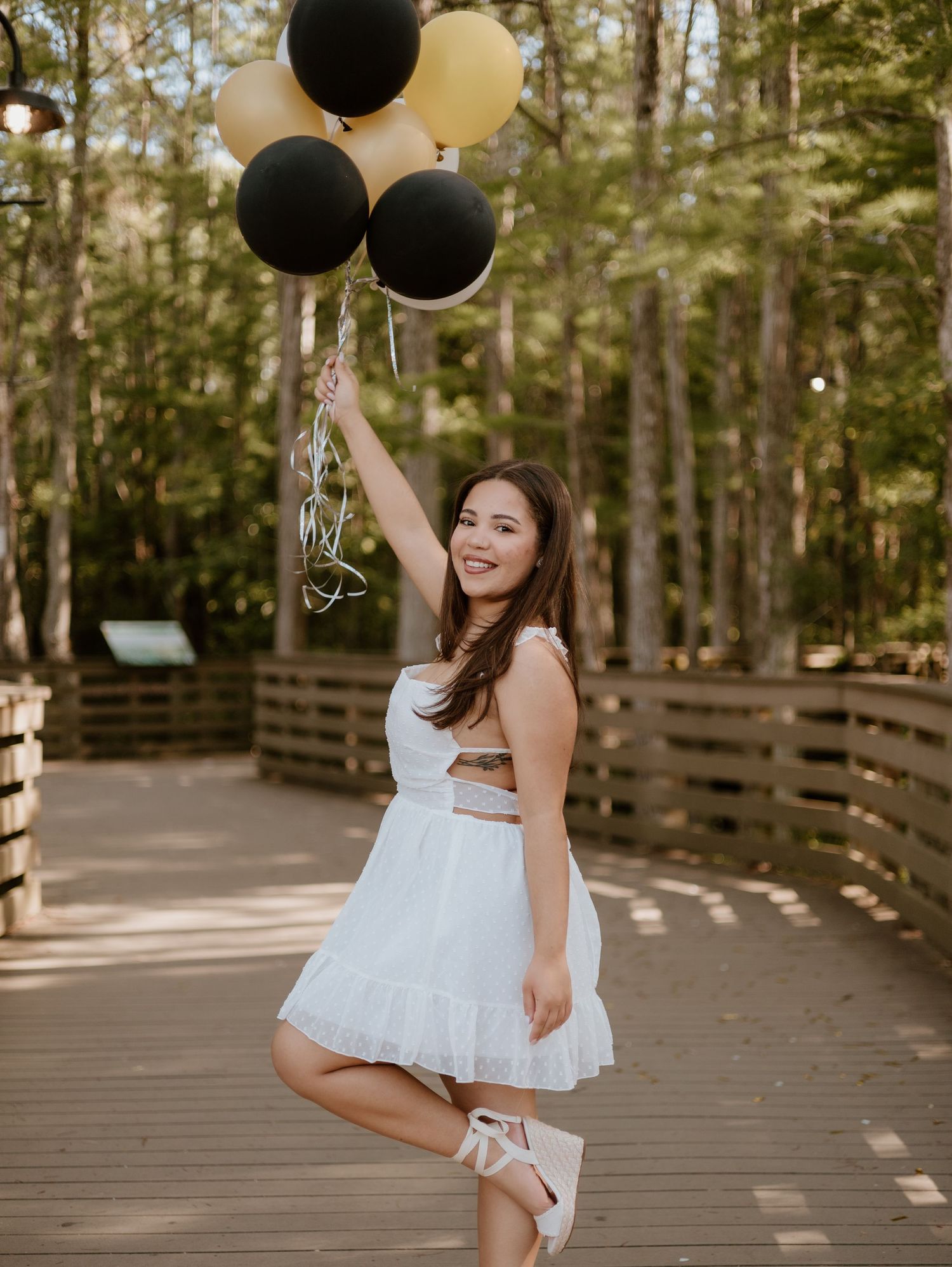 Joyful photo session on a wooden boardwalk with black balloons in a forest setting.