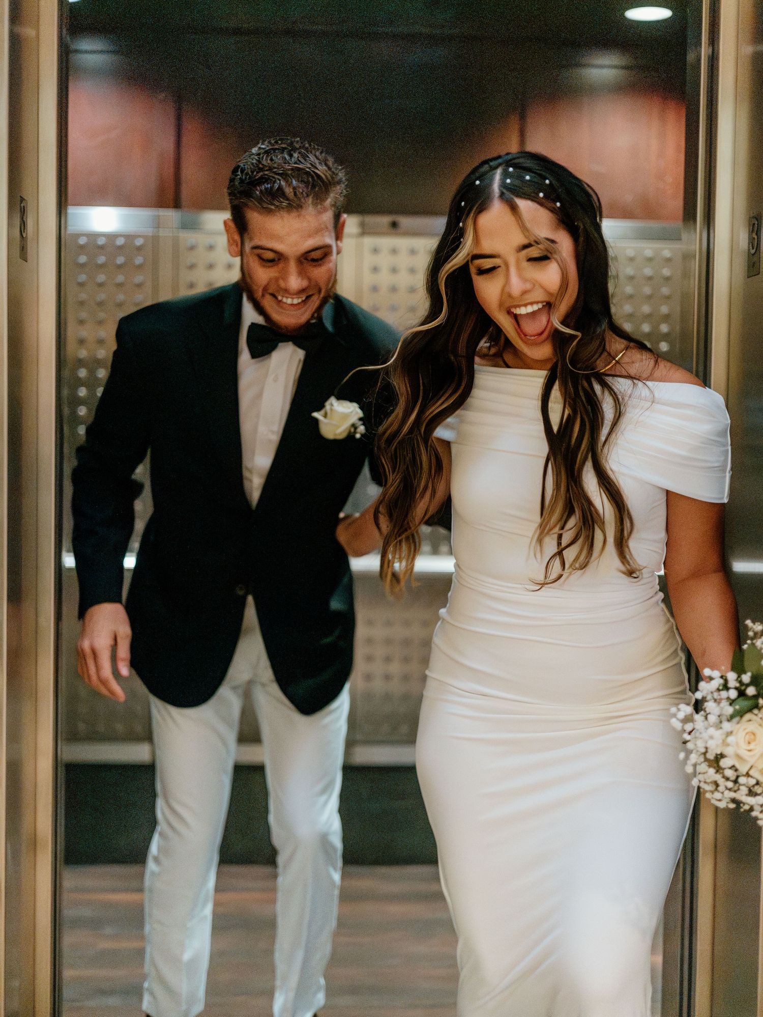 Joyful couple sharing laughter while walking through a modern hallway together.
