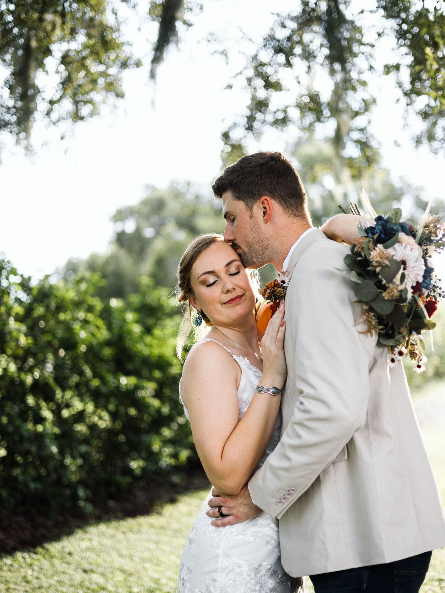 A bride and groom share an intimate embrace while dancing together at an outdoor wedding venue.