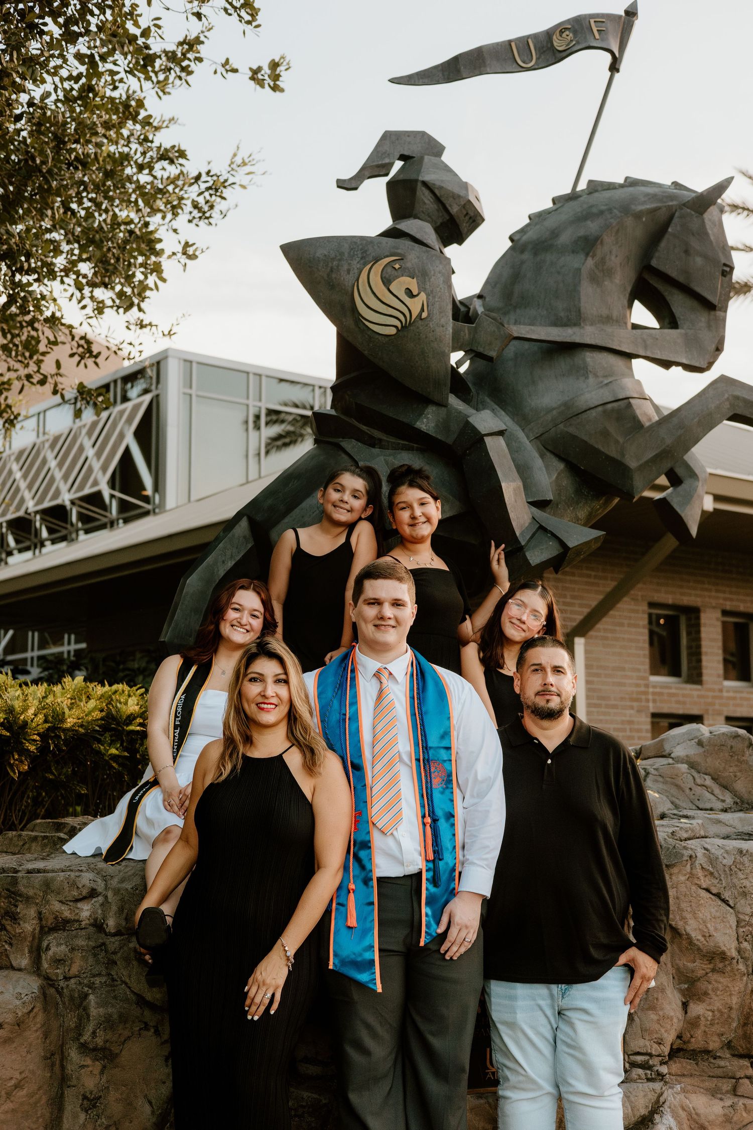 Group posing together near decorative metal horse sculptures at sunset.