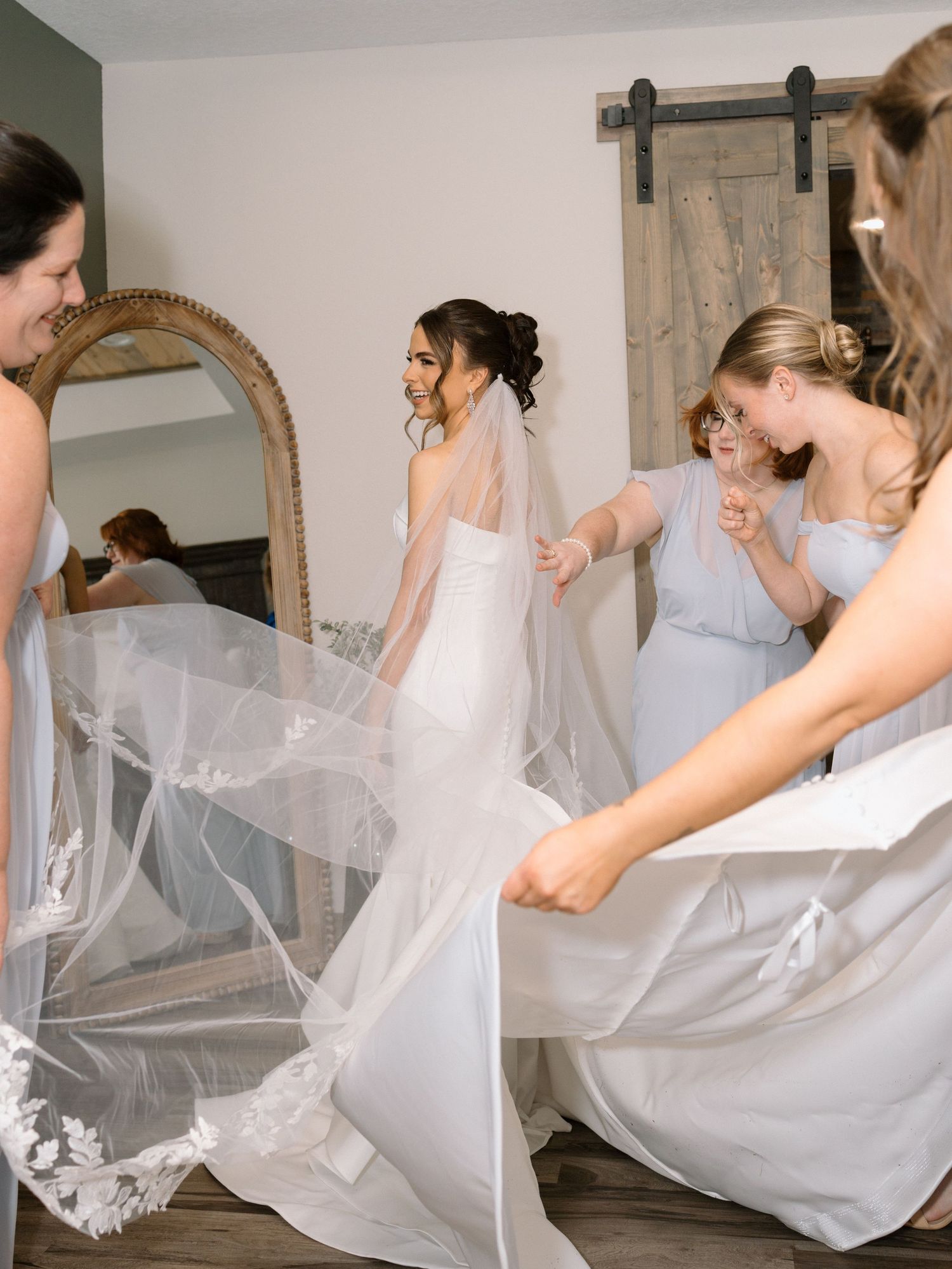 A series of four candid photos showing bridesmaids dressed in white fluttering a wedding veil together in a getting-ready room.