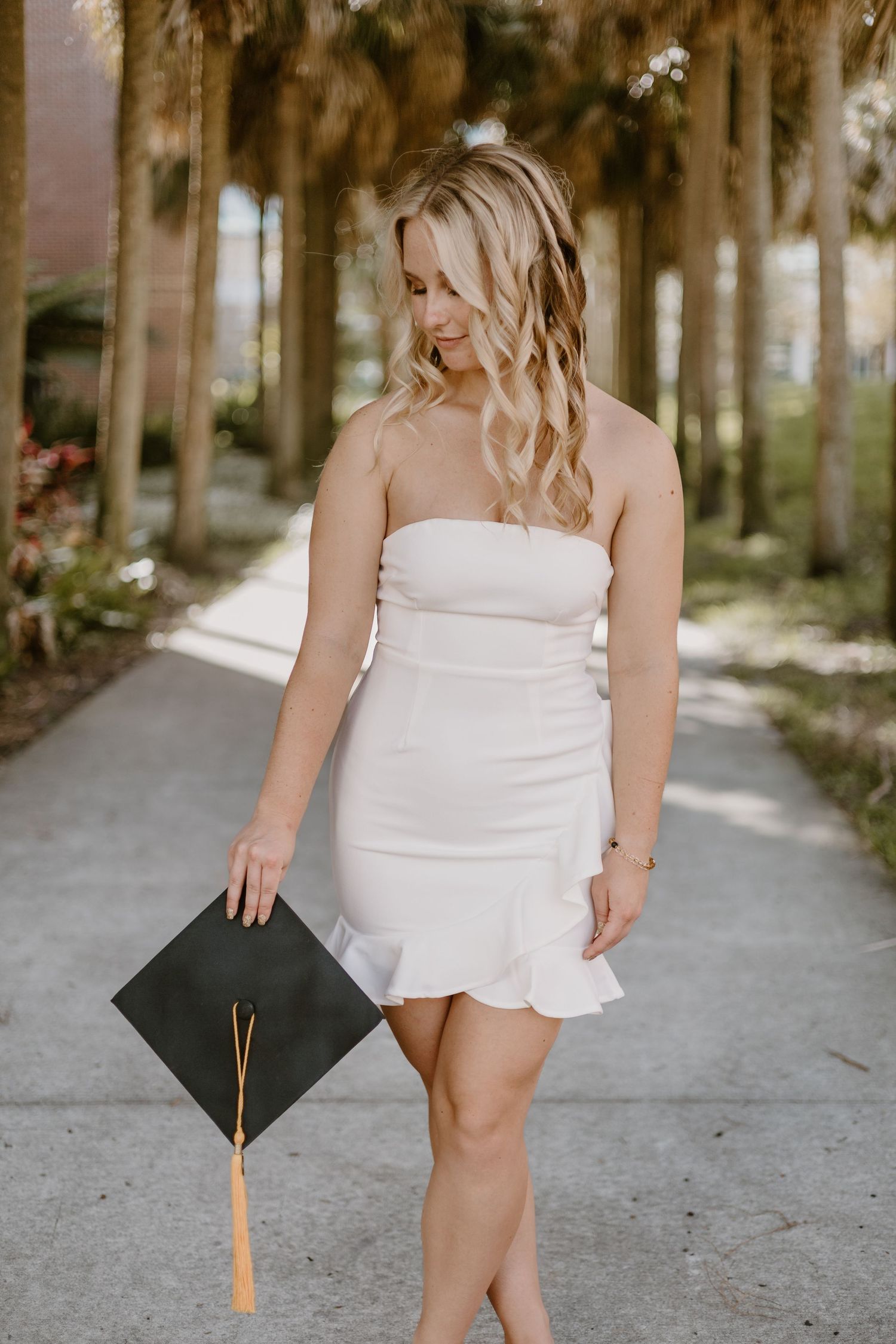 A series of graduation portraits featuring a white dress and graduation cap against a wooded background.
