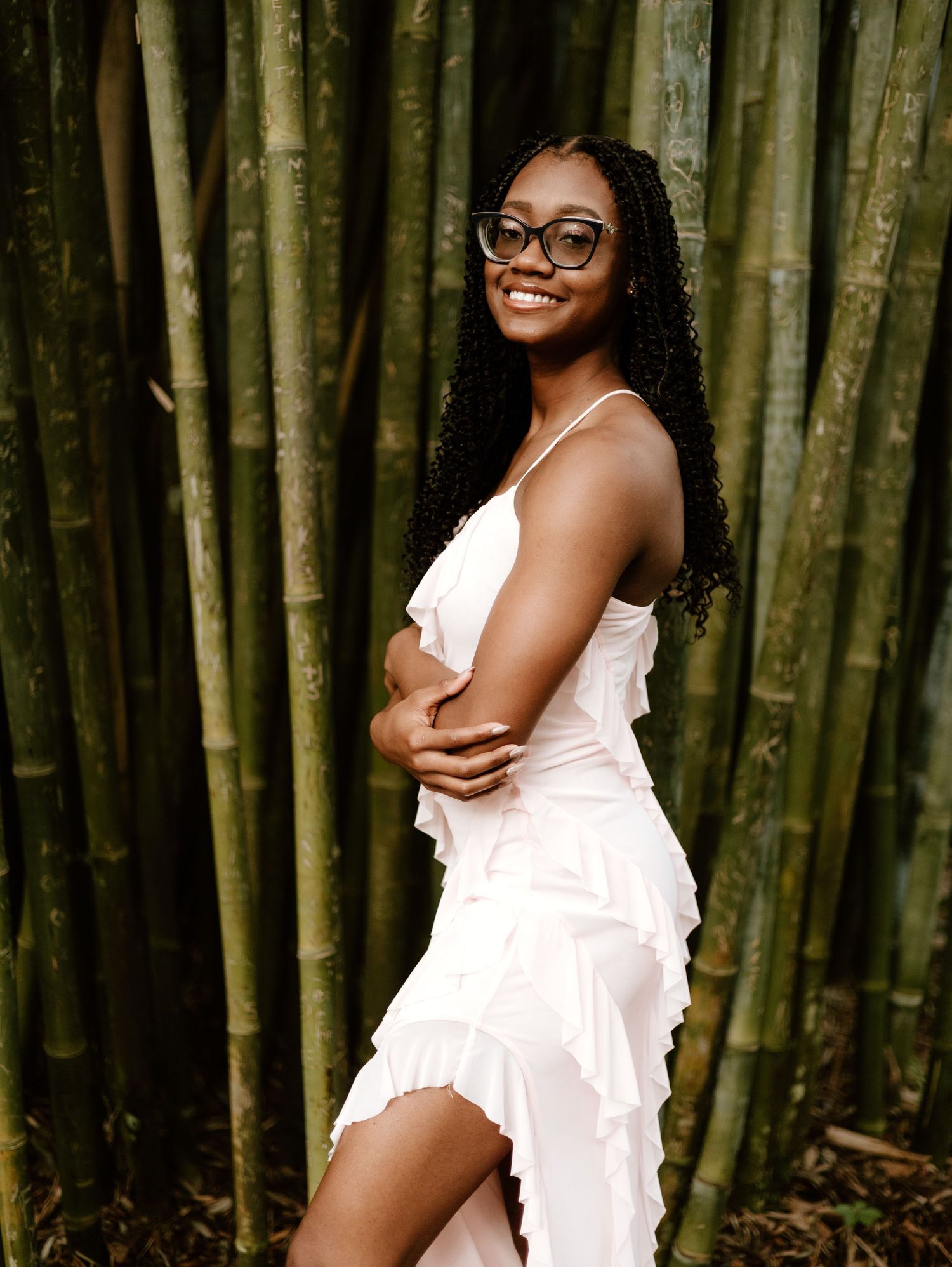 Portrait session among tall bamboo stalks in white dress.