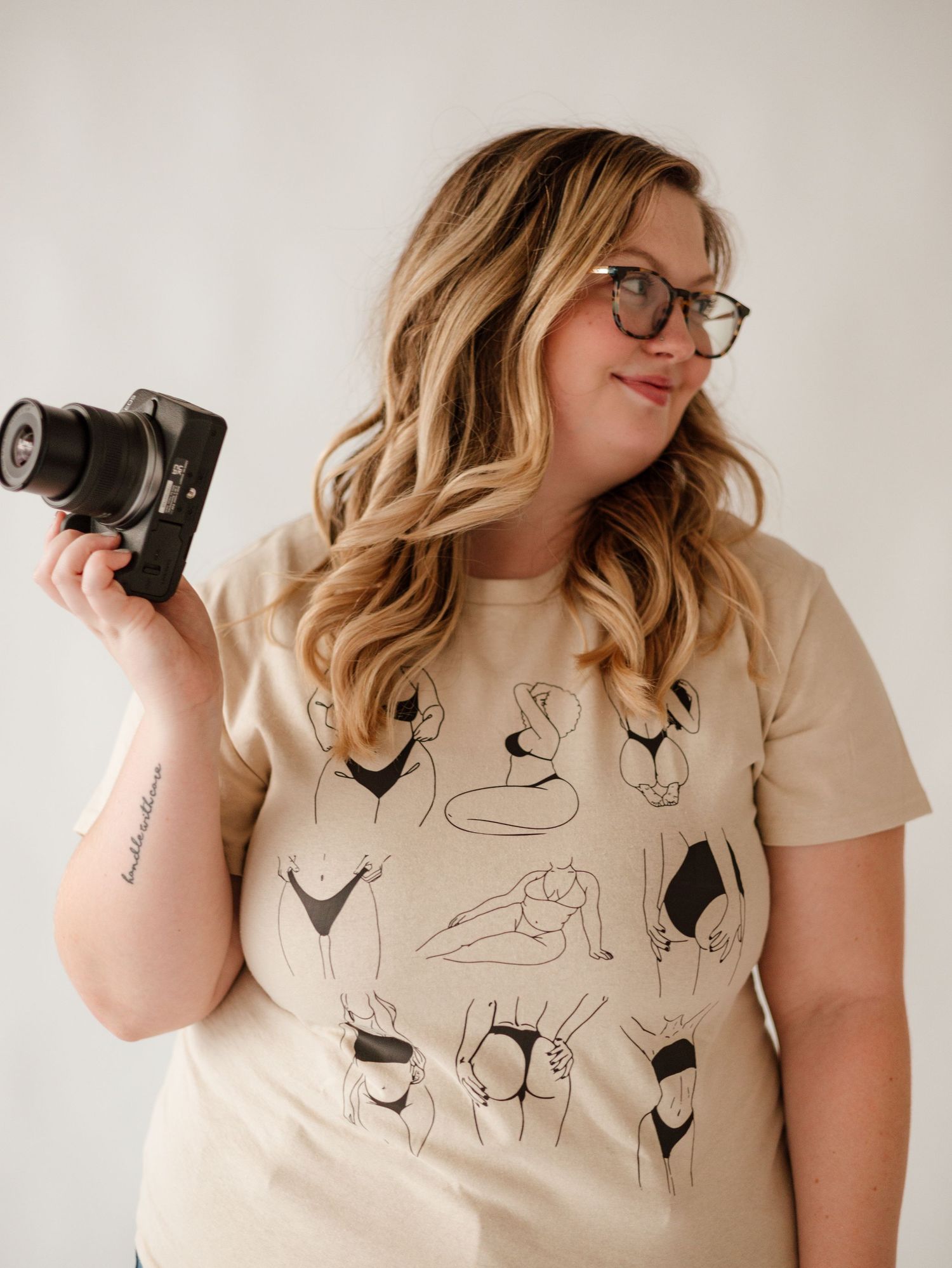 Person wearing a beige t-shirt with minimalist line art designs.