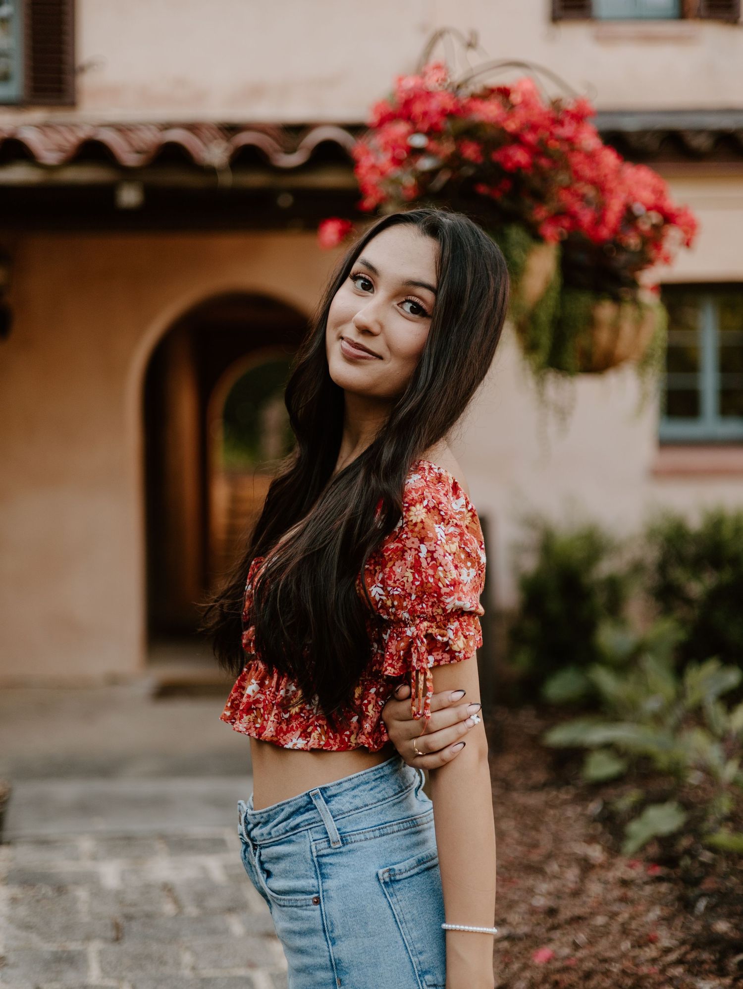 Casual portrait session with pink flowers and Spanish-style architecture in background.