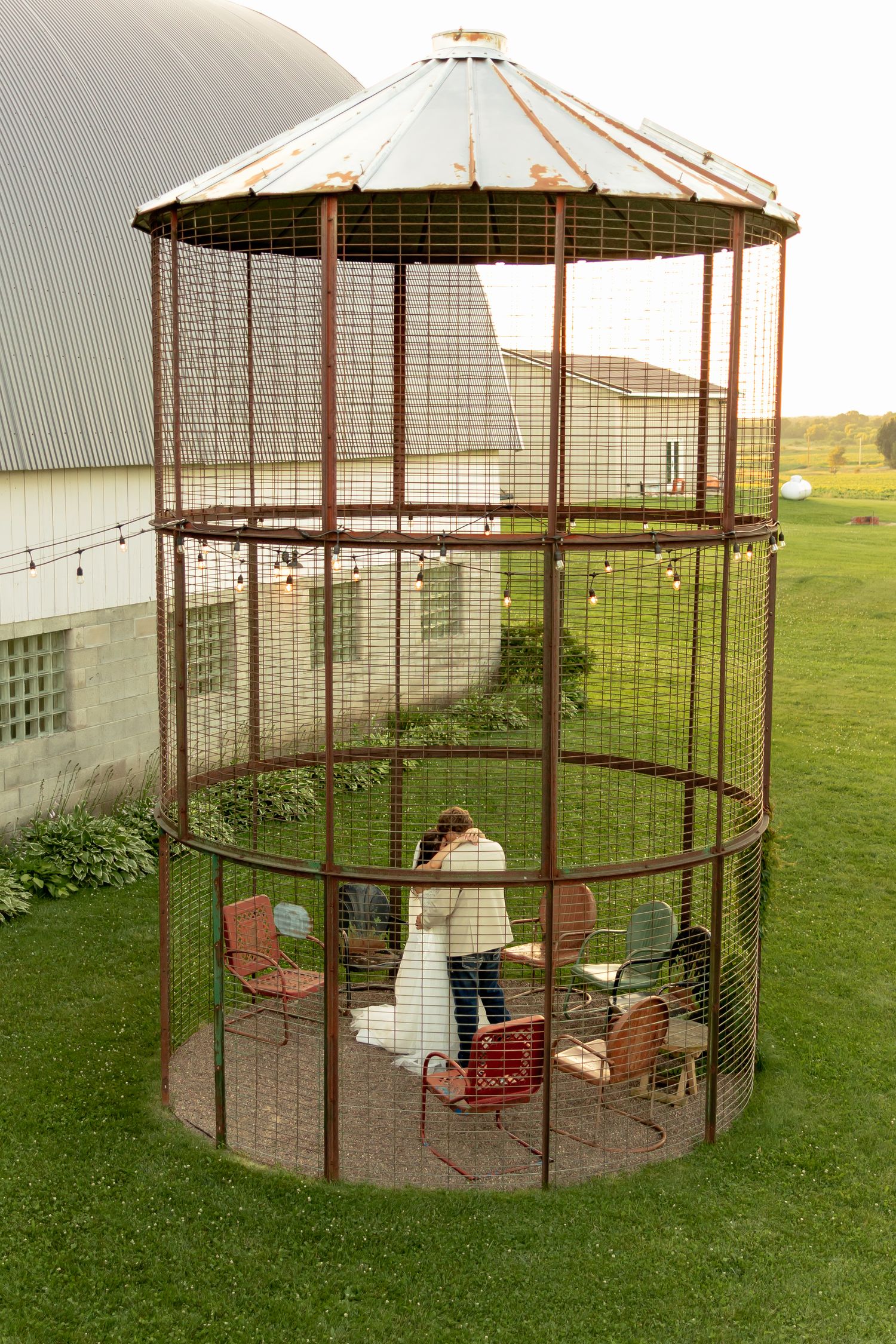 Bride and groom share a romantic moment inside a rustic metal grain bin gazebo on a farm wedding venue.