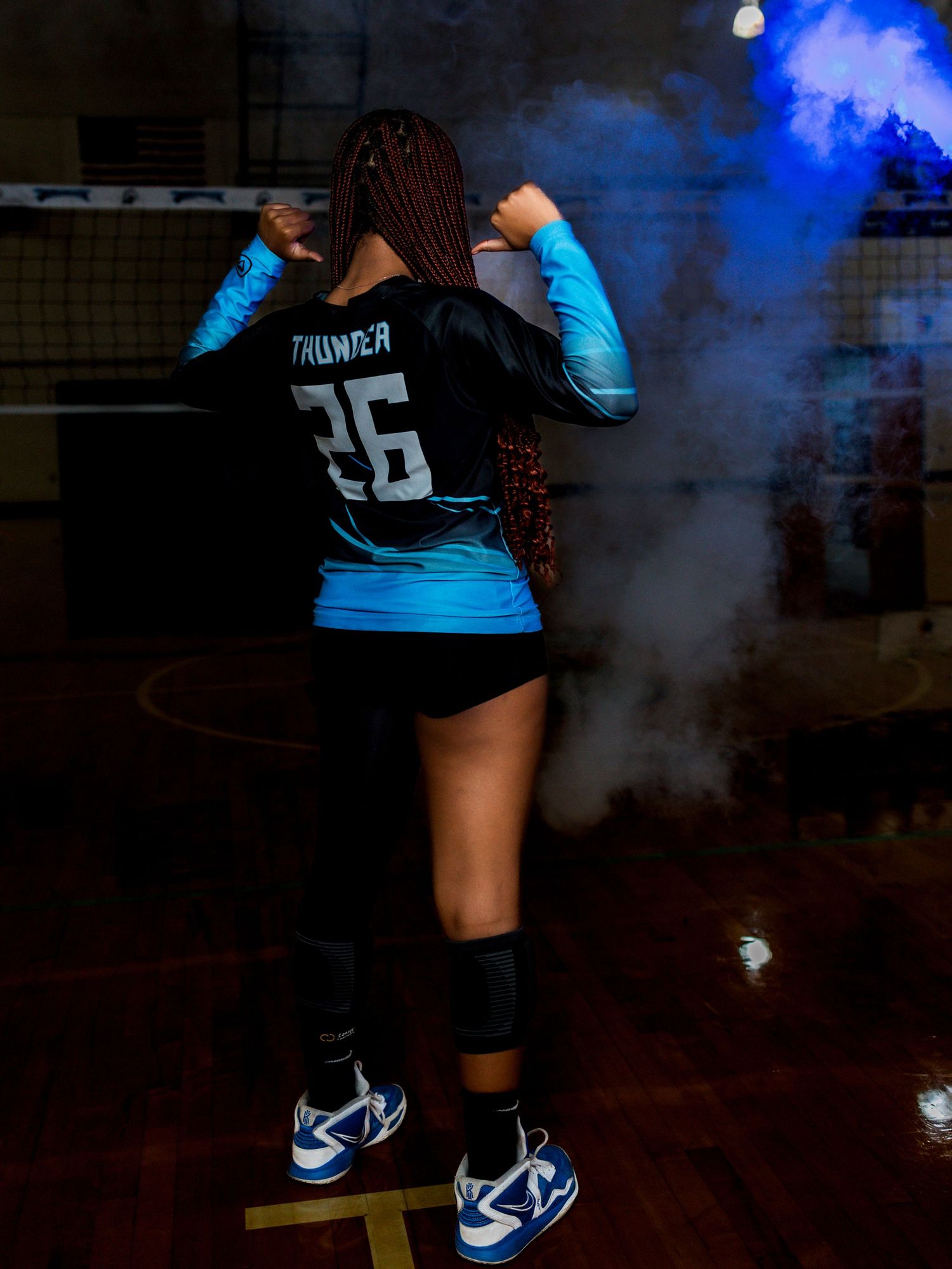 Sports player with jersey number 56 poses in blue and black uniform against smoky backdrop.