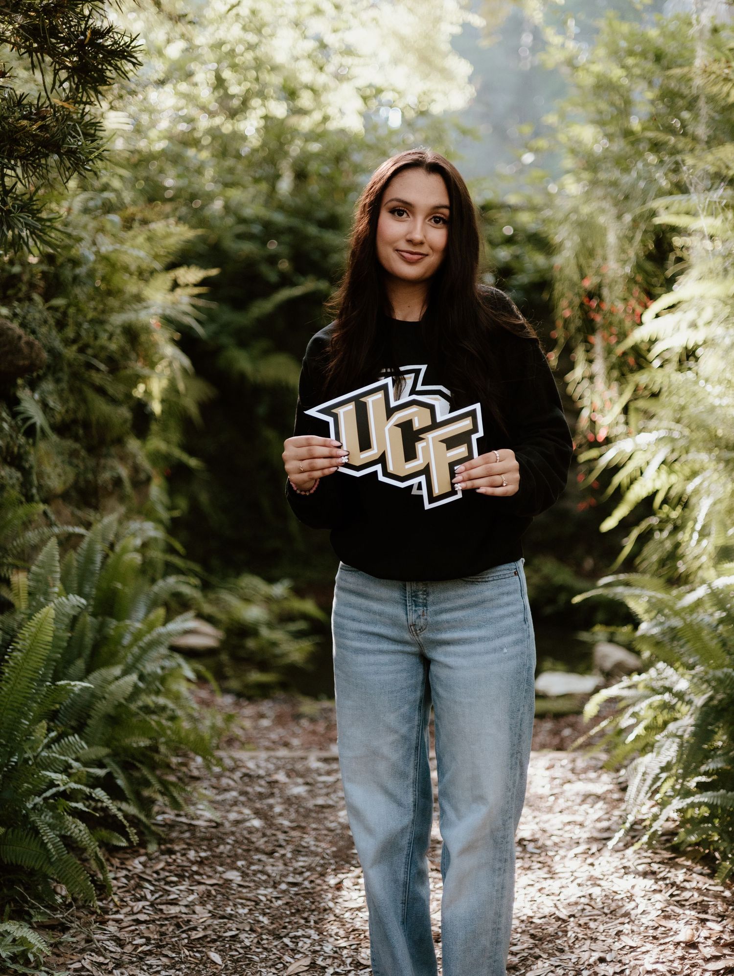 Multiple shots sharing the same frame of someone wearing jeans and a dark sweatshirt posing on a wooded forest trail.