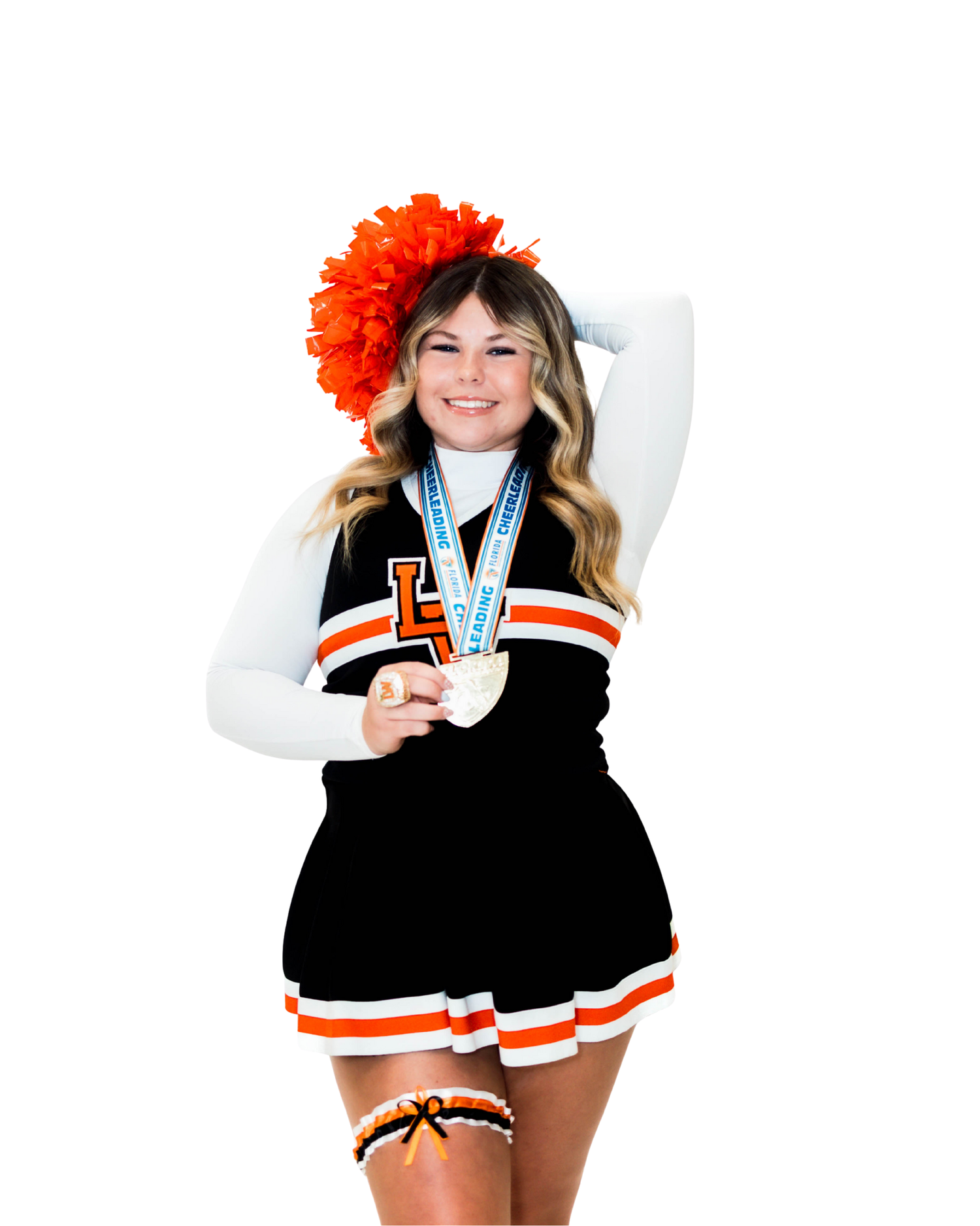 A cheerleader in black and orange uniform poses with pom poms during a sports performance.