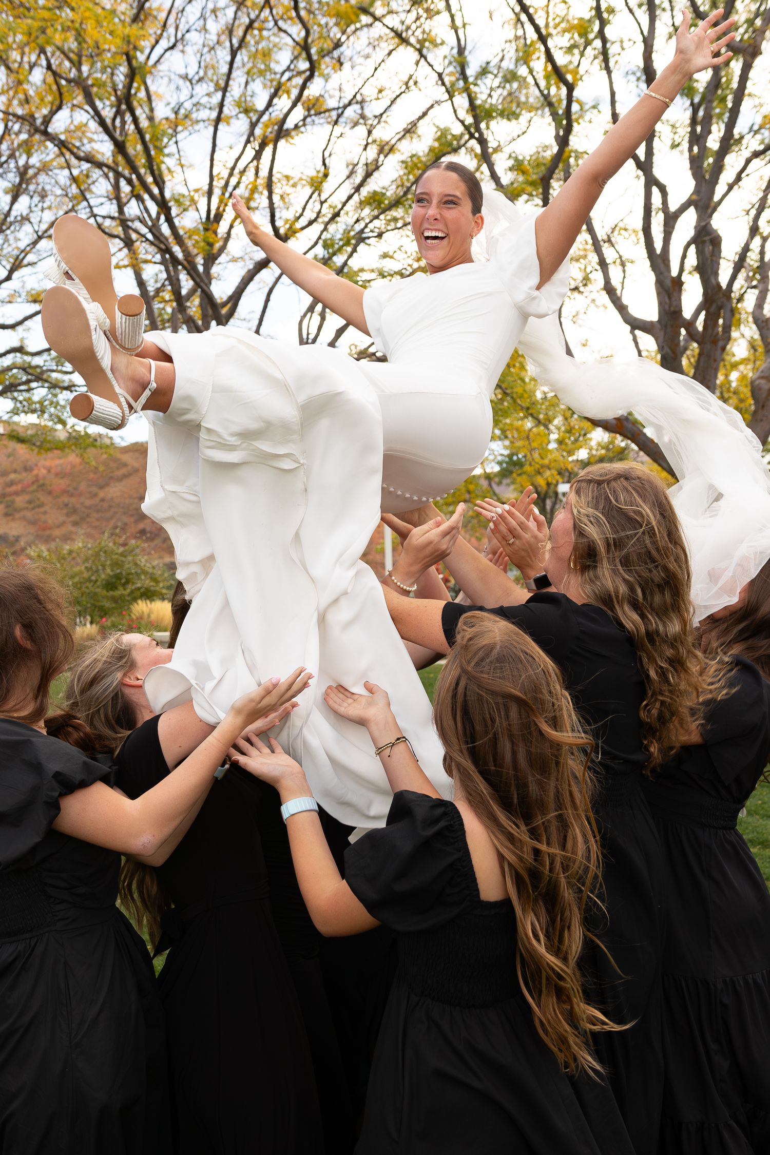 A bride being thrown into the air by her bridesmaids