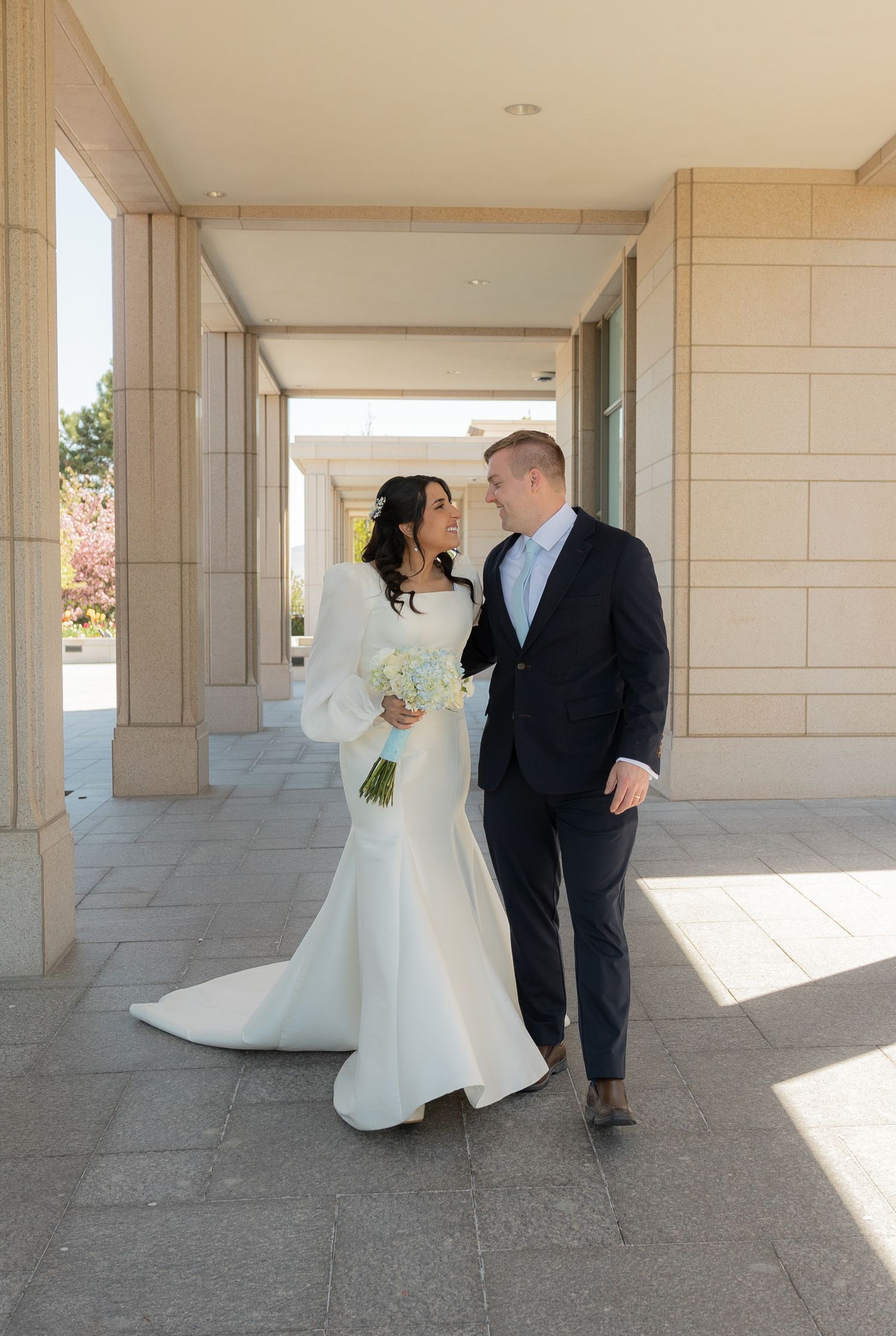 A bride and groom walking by the Oquirrh Mountain Utah Temple