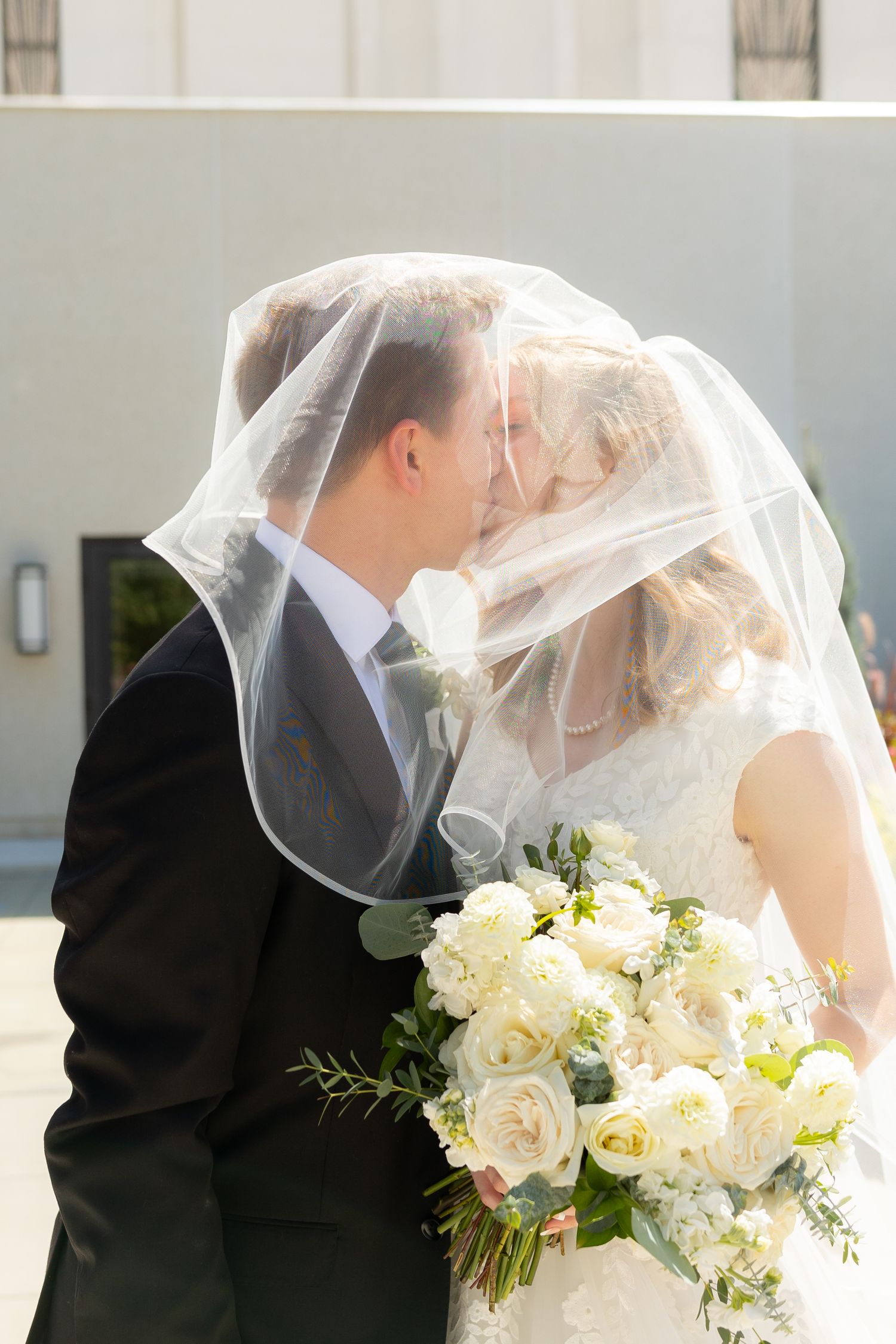 A bride and groom kissing under the bride's veil