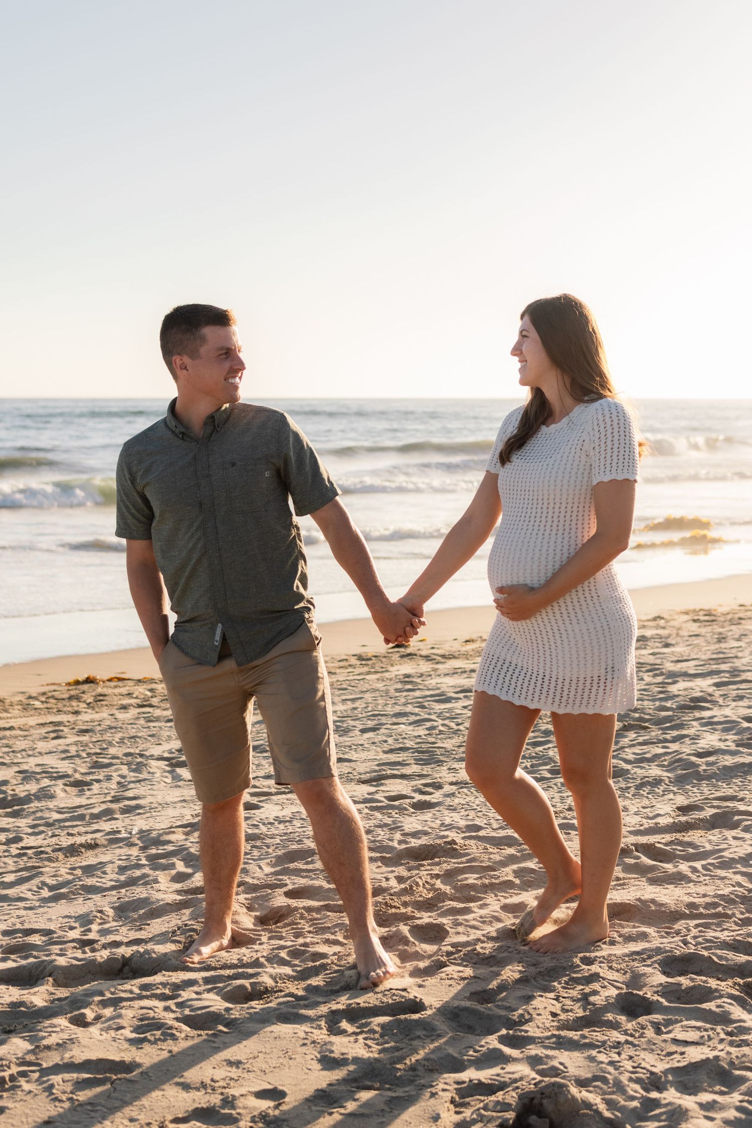 A man and his pregnant wife on a beach
