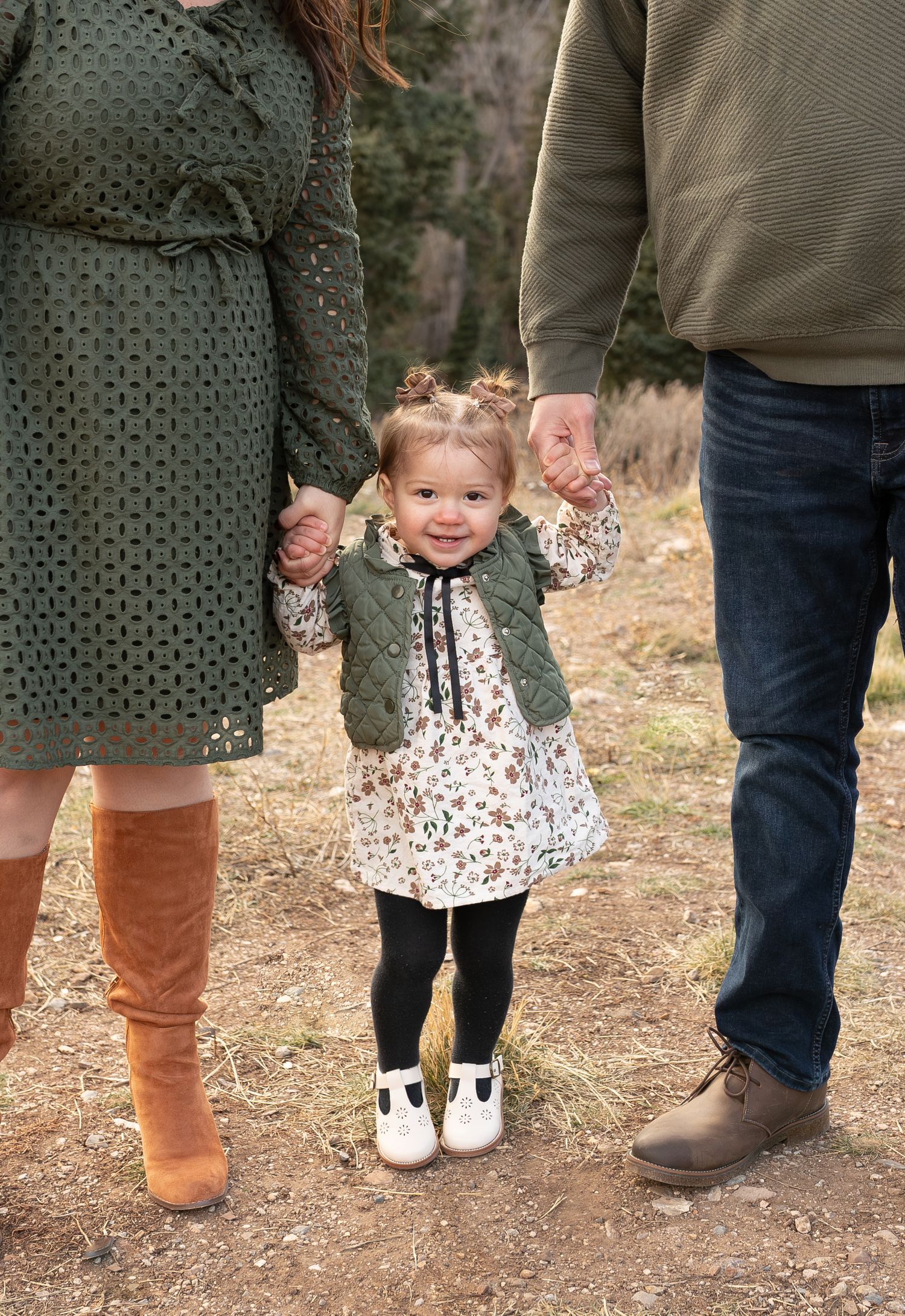 Photo of a toddler holding her parents hands