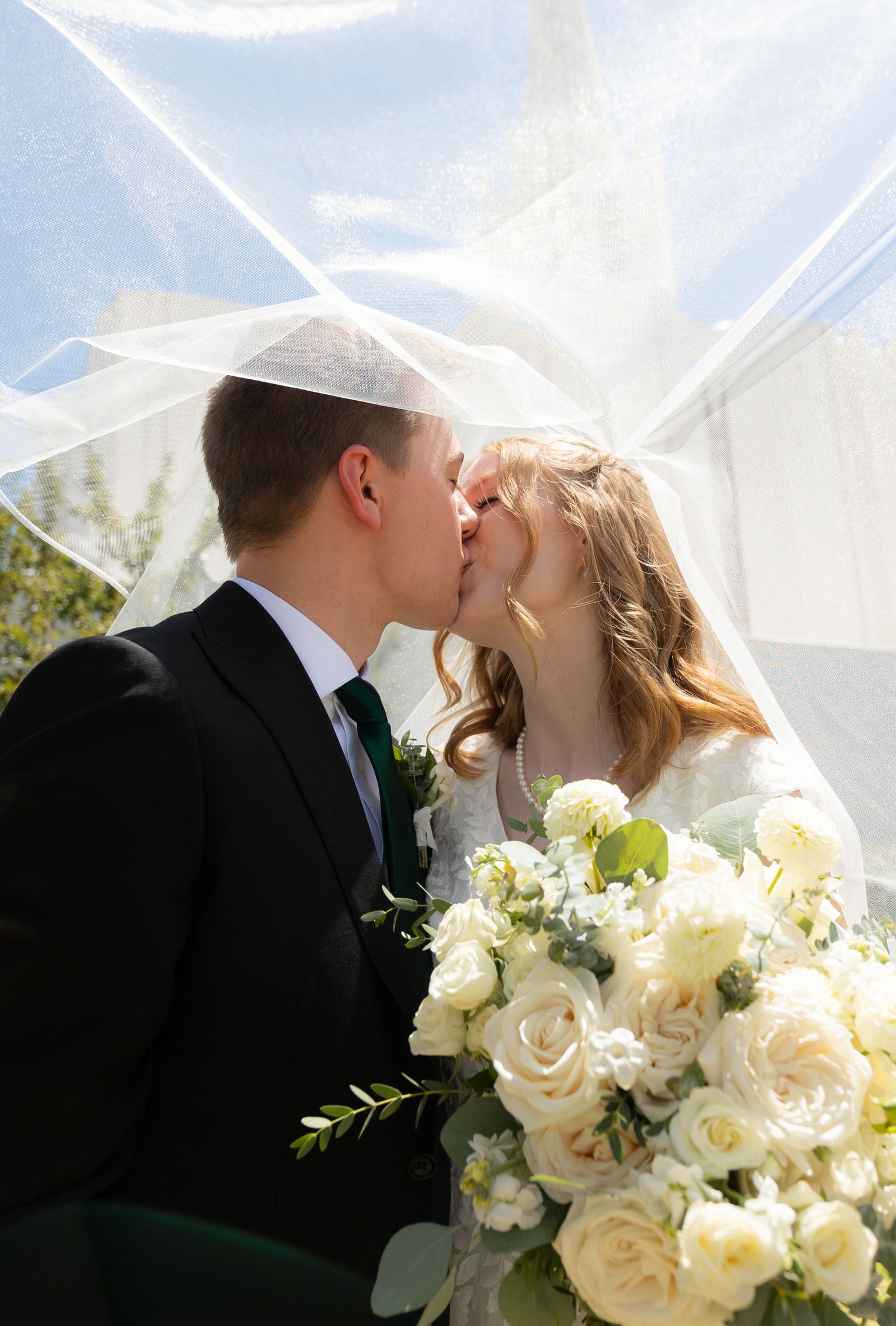 A bride and groom kissing under the bride's veil
