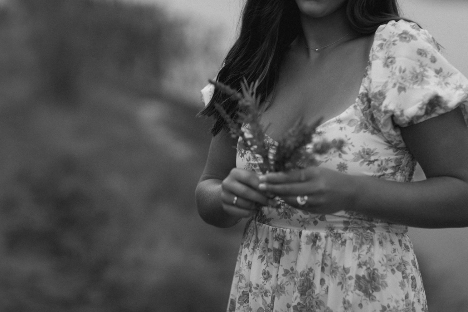 A person in a white floral dress holds a flower during senior photoshoot in keene, new hampshire