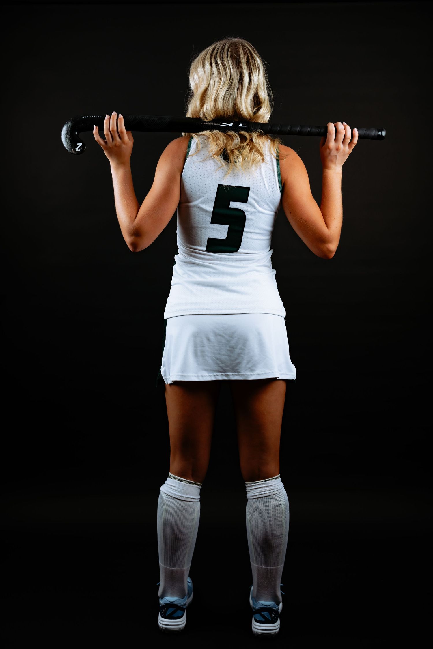 Athlete in white jersey with number 5 performing workout sequence against dark backdrop in New Hampshire photography studio.