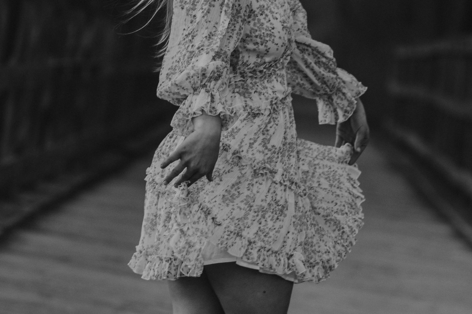 Black and white photo series shows elegant ruffled floral dress details on a model walking down a path at Keene State College.
