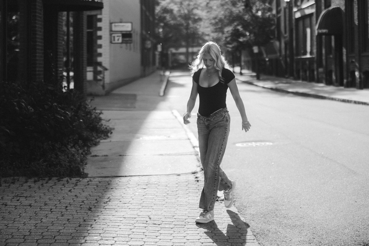 Monochrome urban street portrait on a sunlit sidewalk among buildings and shadows senior high school photoshoot Keene, New Hampshire