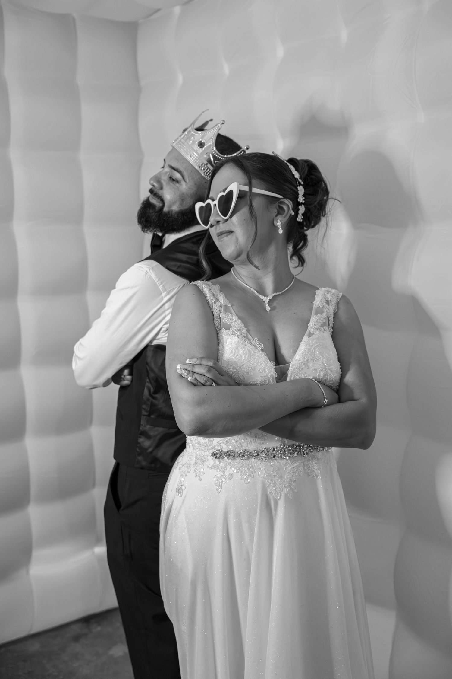 Bride and groom posing playfully in black and white with fun photo booth props and sunglasses.