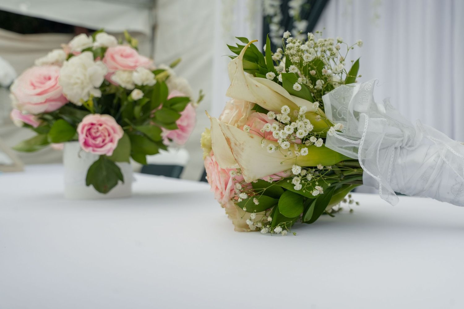 Beautiful wedding bouquet with pink and white roses and baby's breath on white table at reception.