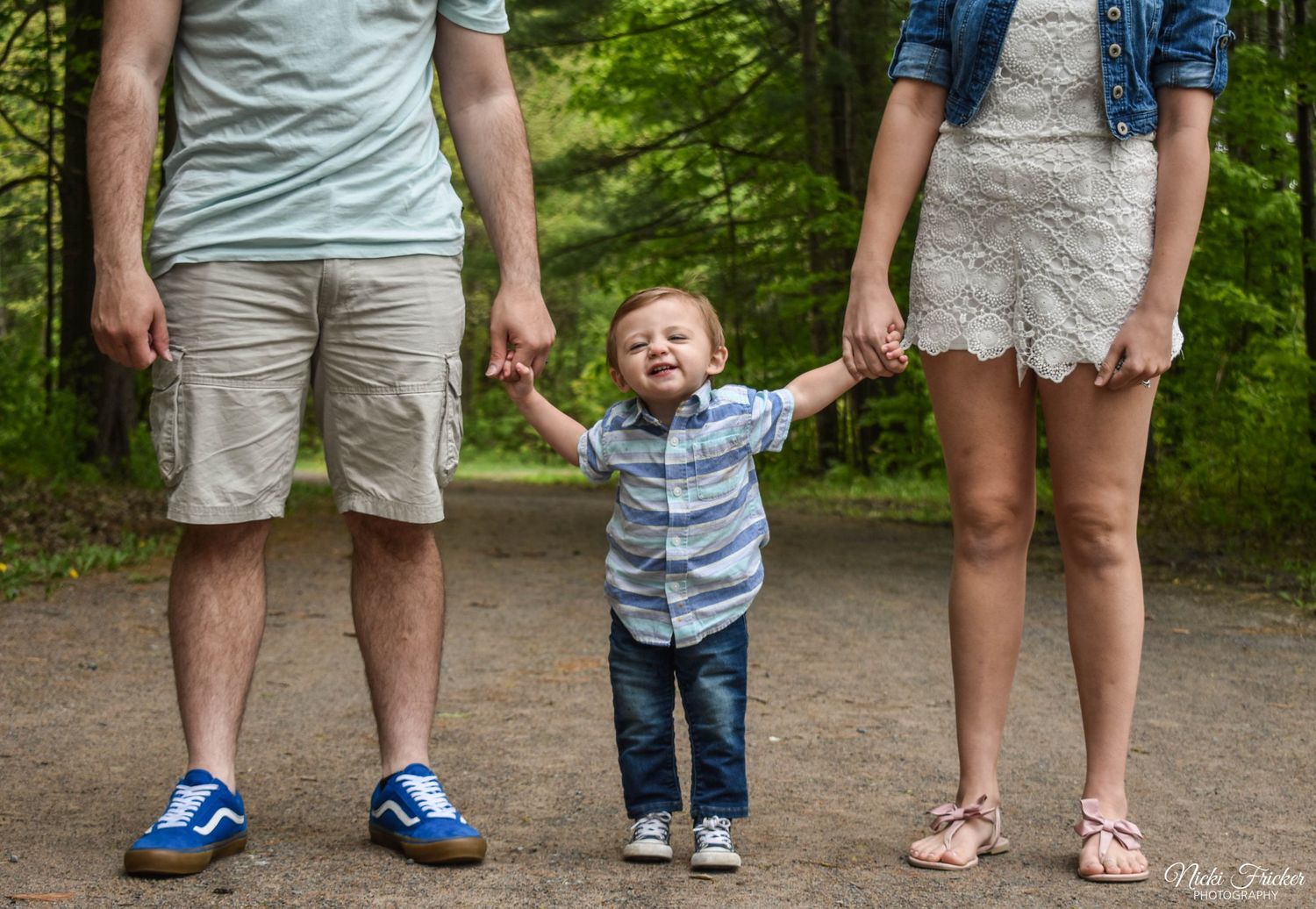 Close-up view of legs and feet of people standing together on a path outdoors.