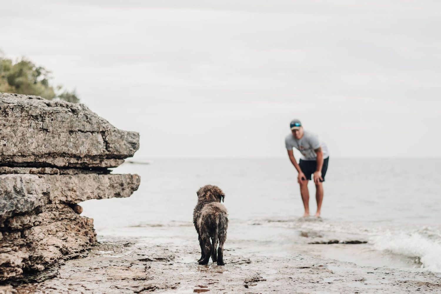Couple explores rocky beach shoreline during engagement photo session.