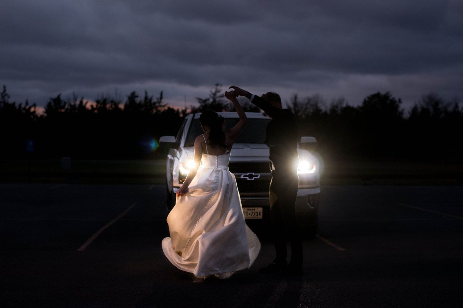 Silhouetted couple embraces during sunset engagement photo session on a beach.