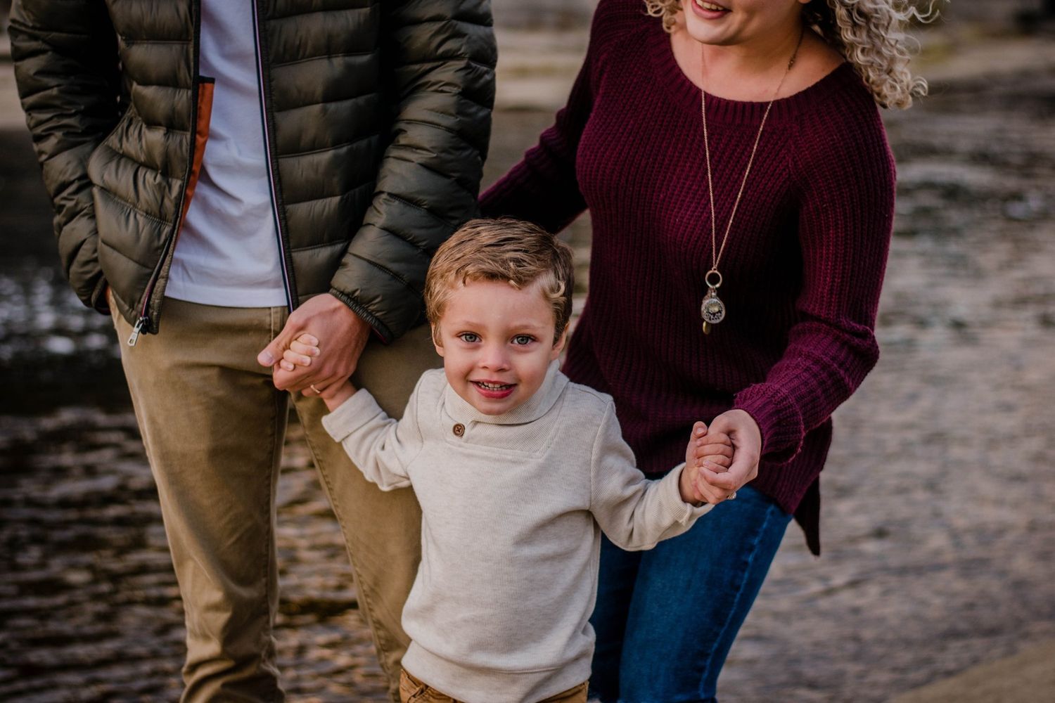 Family wearing coordinated burgundy and neutral outfits poses together outdoors.