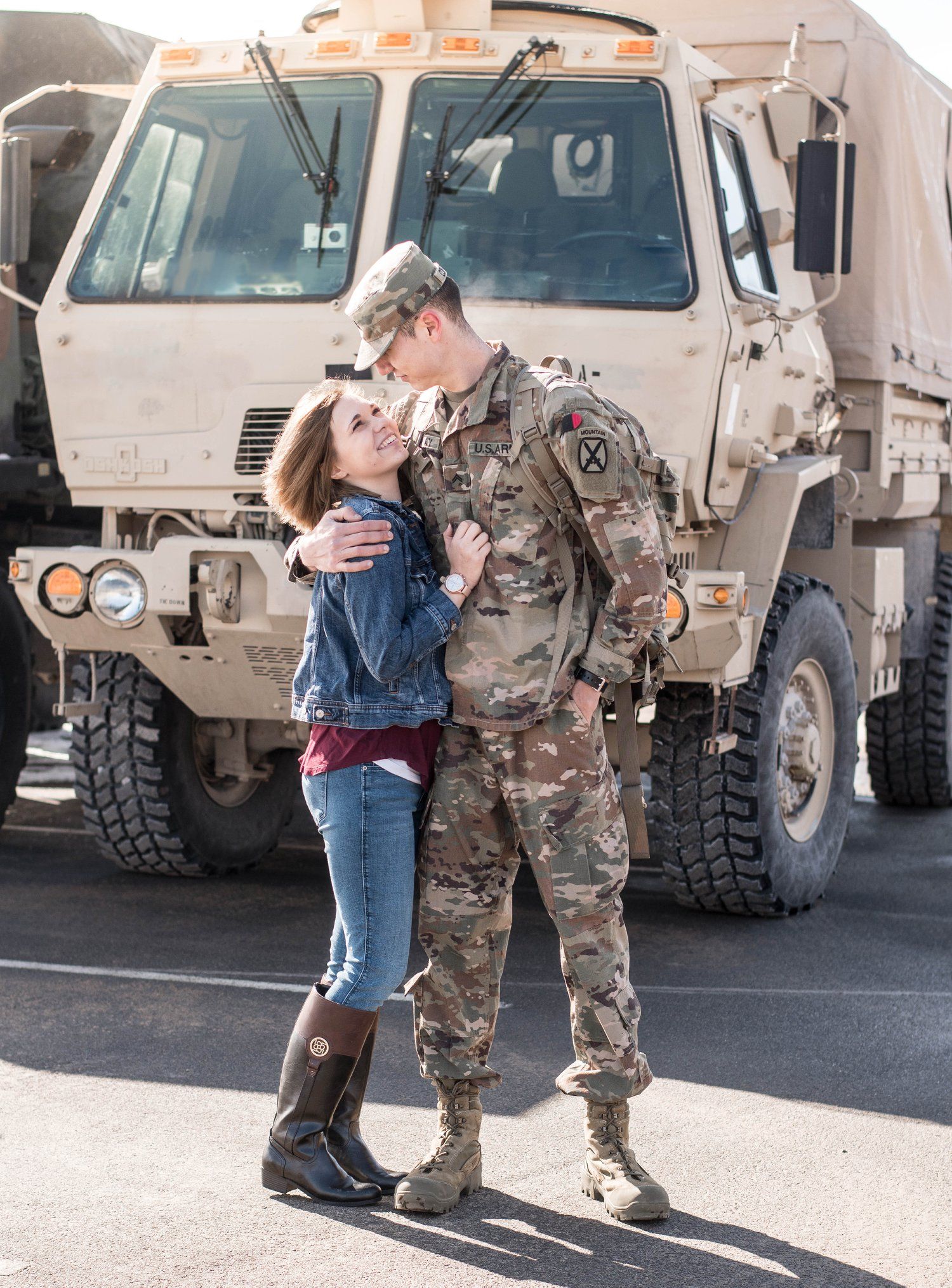 Military reunion scene with military vehicles and emotional embraces in a parking lot.