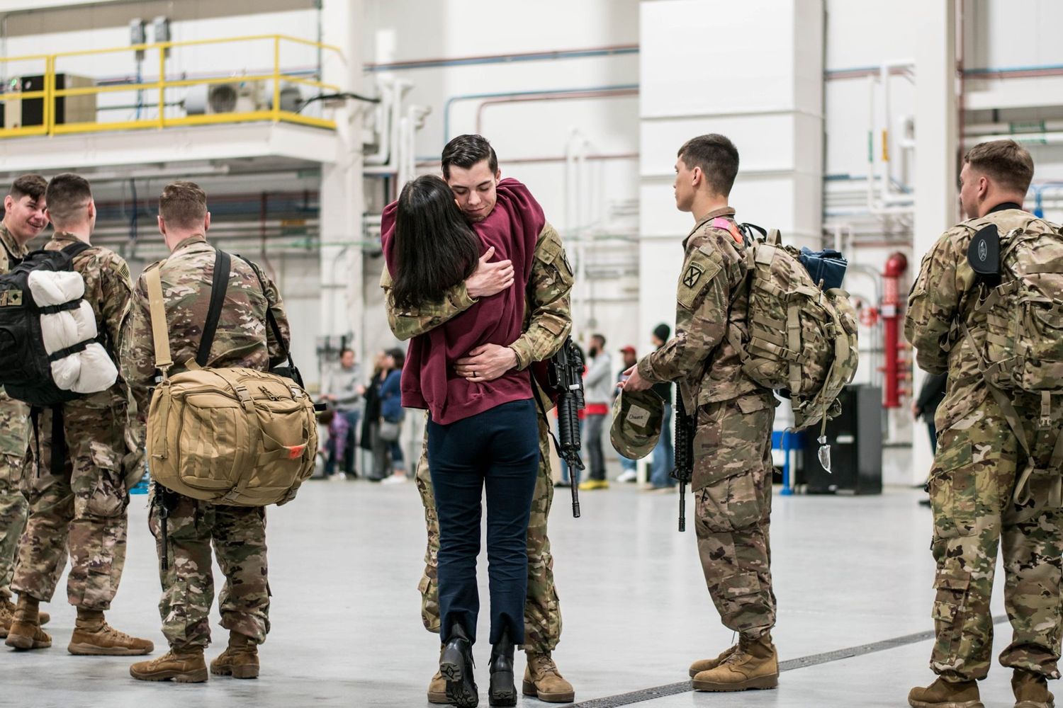 Military homecoming scene in airport terminal with soldiers reuniting with loved ones.