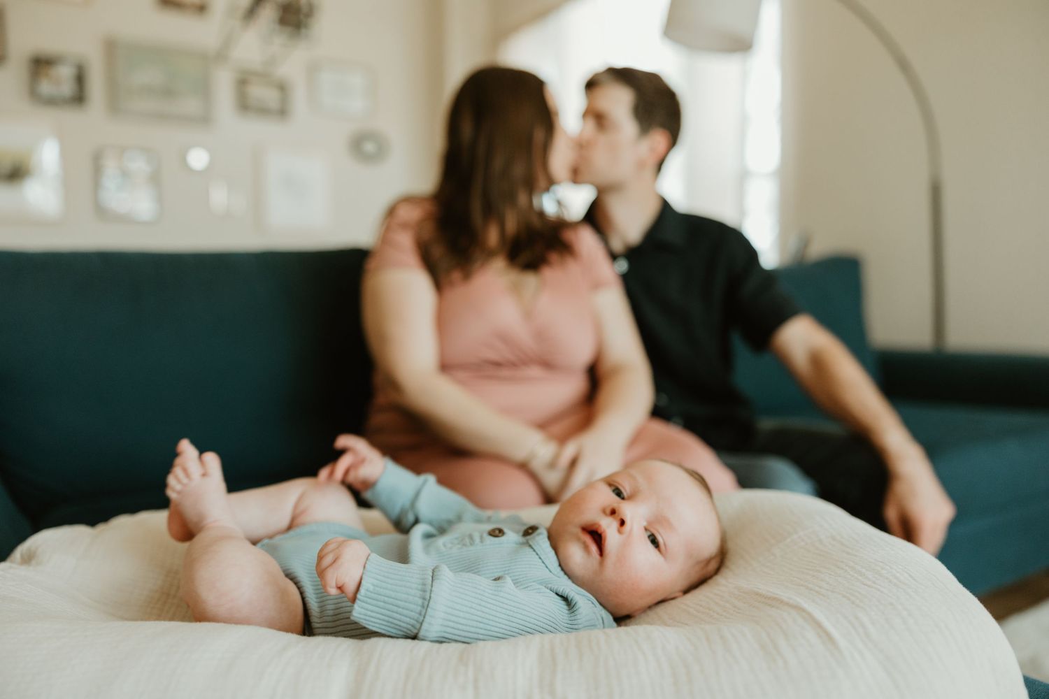 Baby in lounger, mom and dad kissing in background, Austin In-Home Photographer