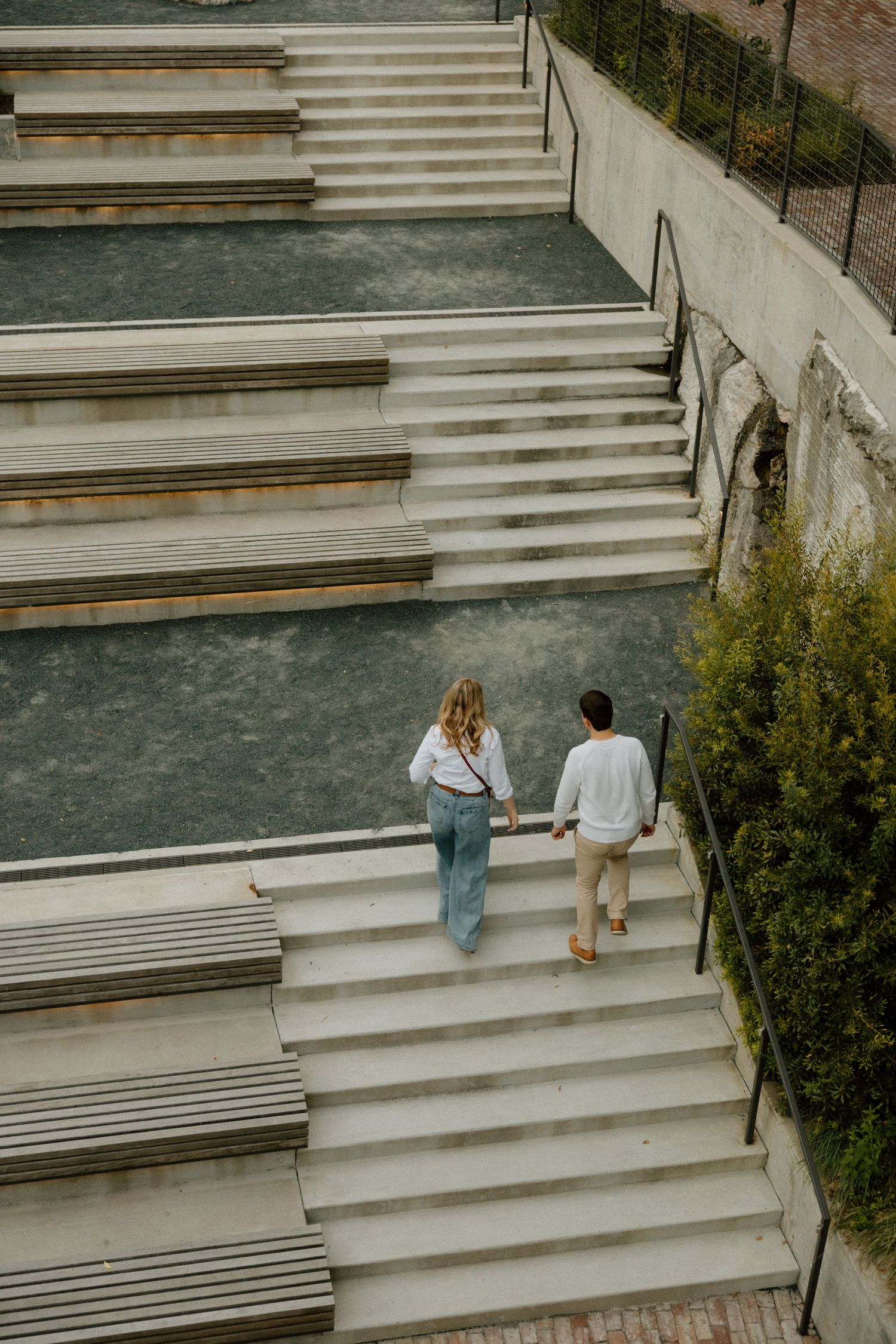 Two people sitting on concrete steps in casual attire during a sunny afternoon.