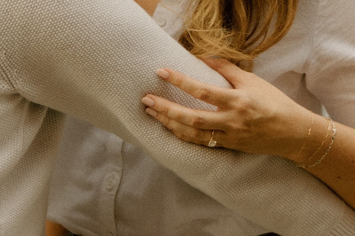 Close-up detail of hands gently touching light colored fabric.