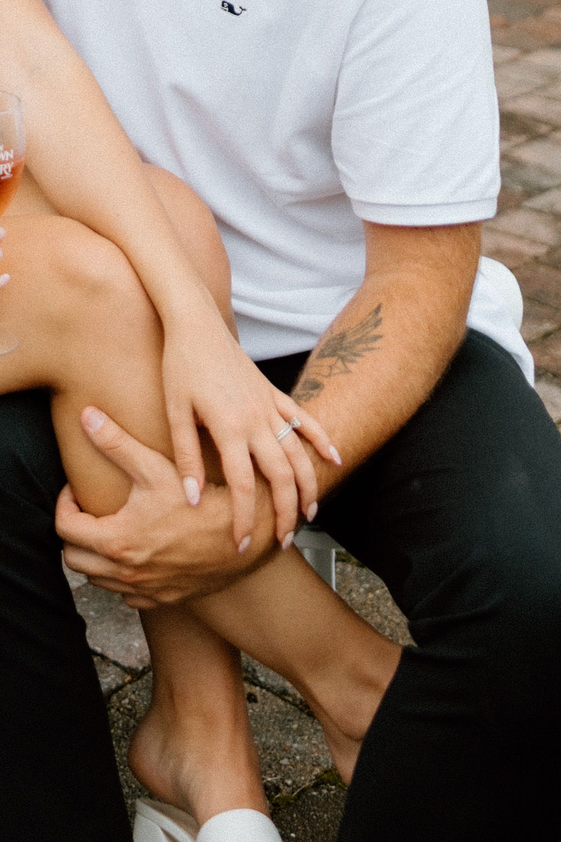 Close-up of hands with tattoo and engagement ring.