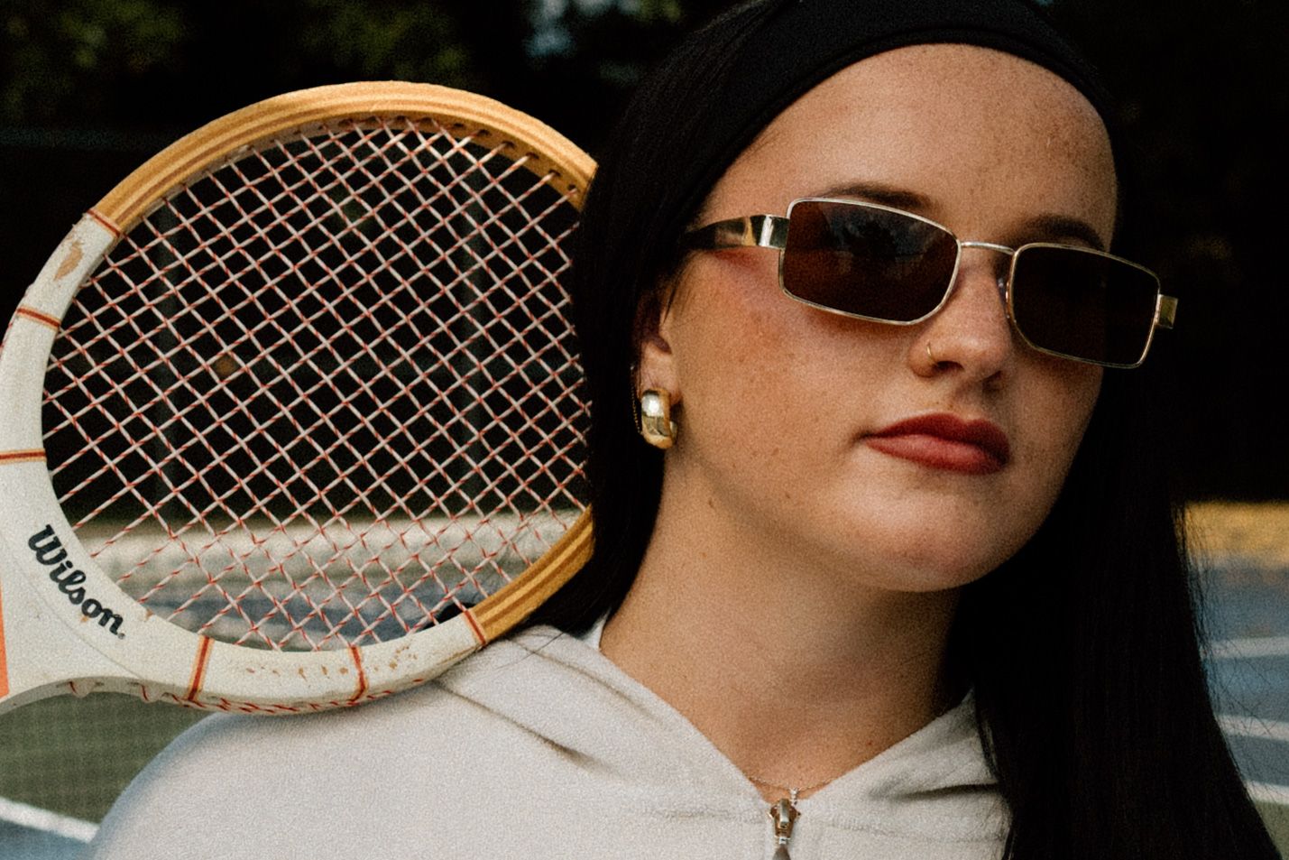 Vintage tennis rackets photographed against dark background with sunlit styling.