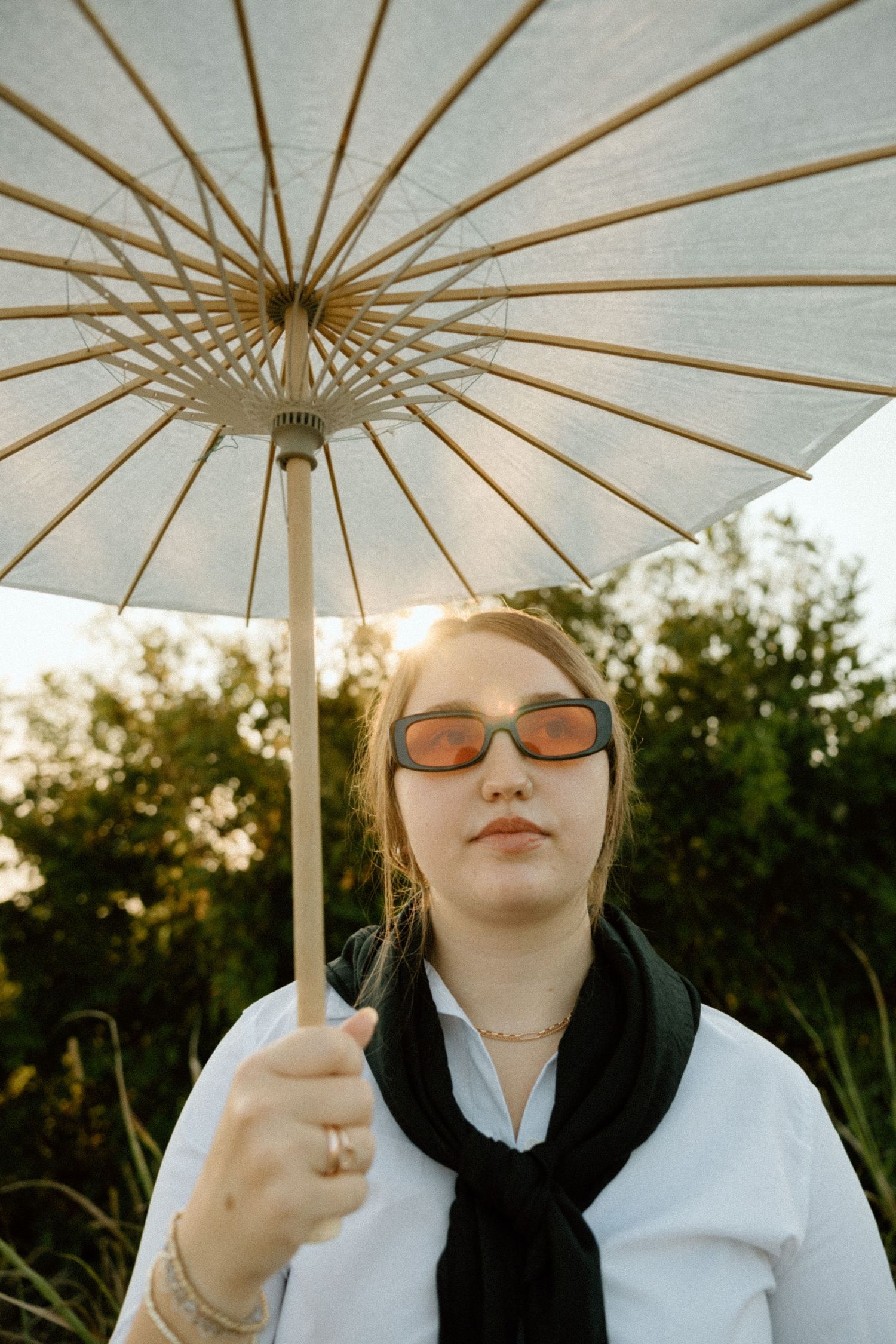 Close-up shots under a white paper parasol showing stylish sunglasses and dark headwear.