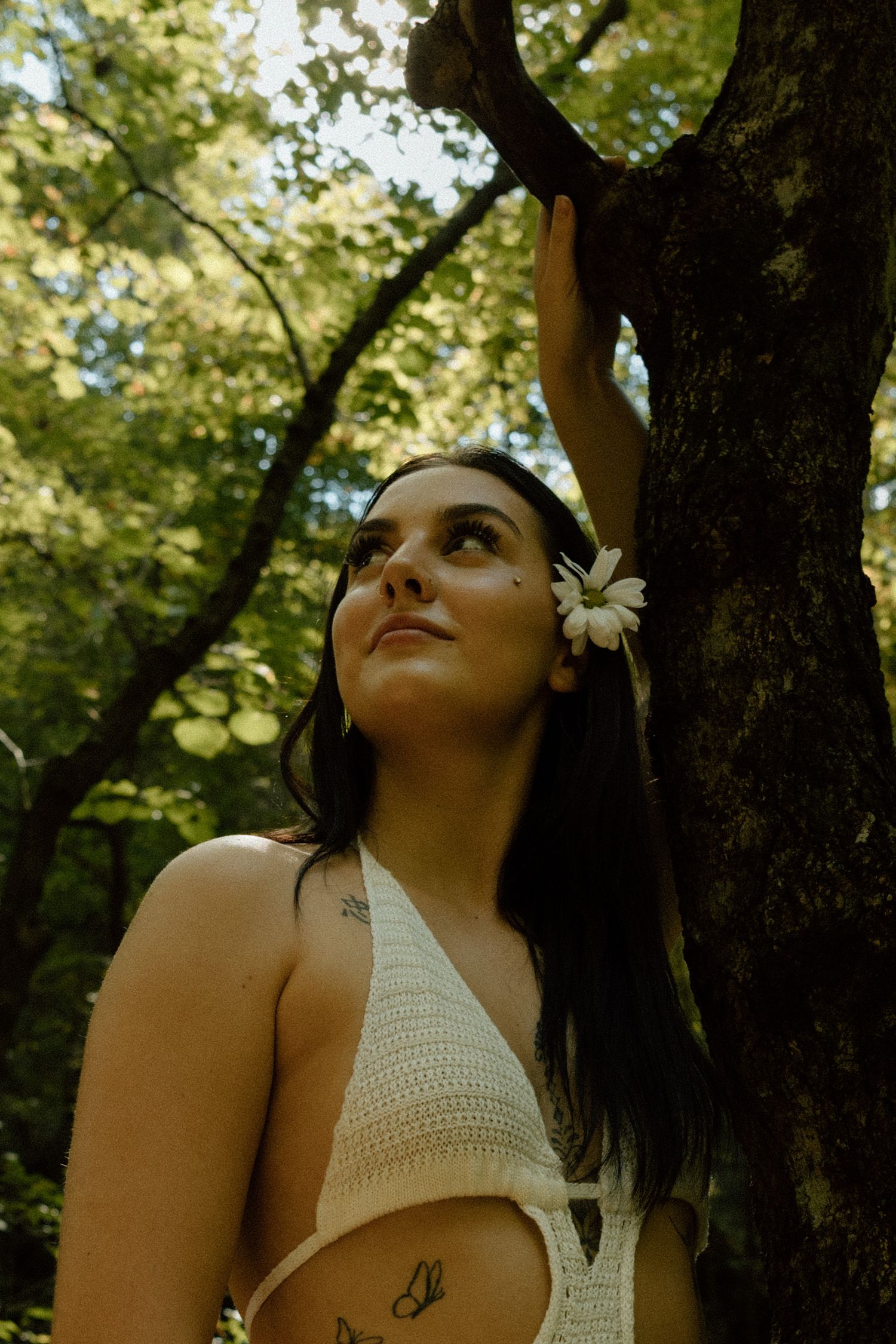 Artistic outdoor photography with white flower accent against forest backdrop.