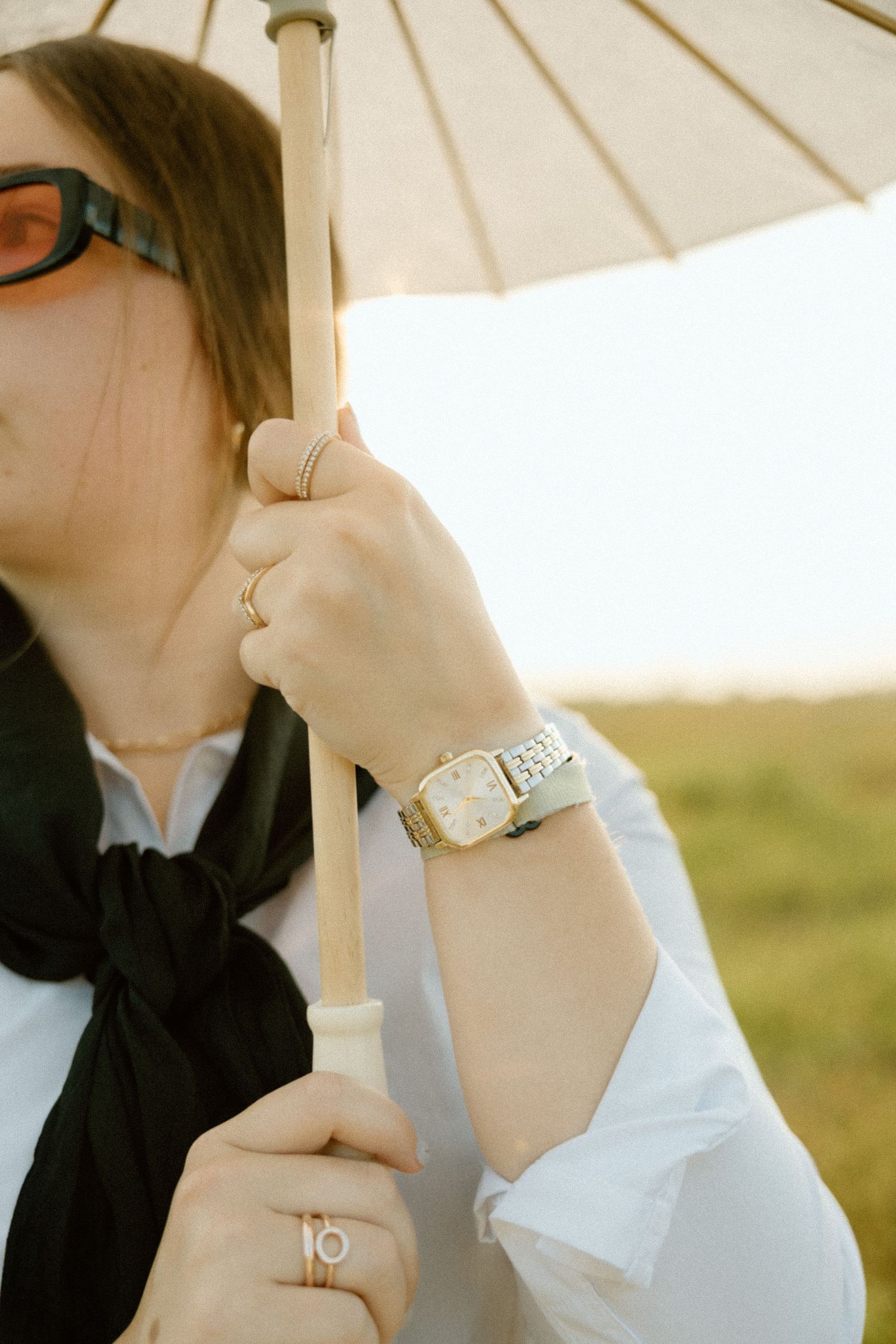 Elegant jewelry and accessories styled under white parasol in natural lighting.