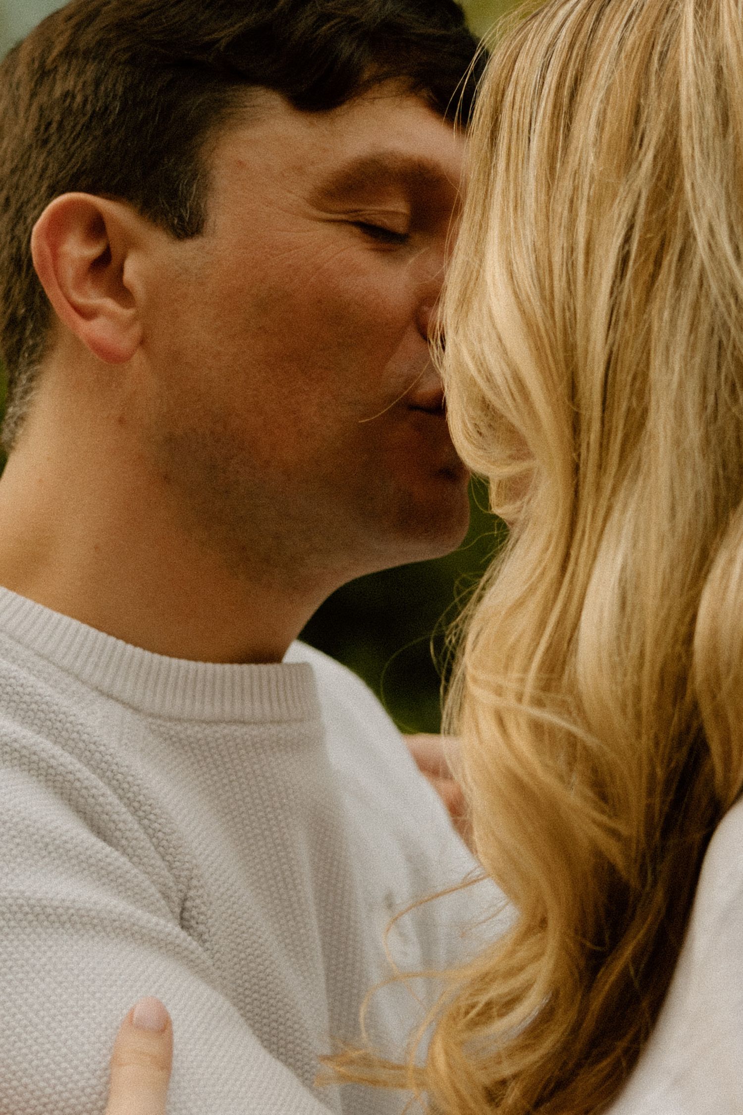 Intimate close-up of couple sharing a tender moment outdoors.