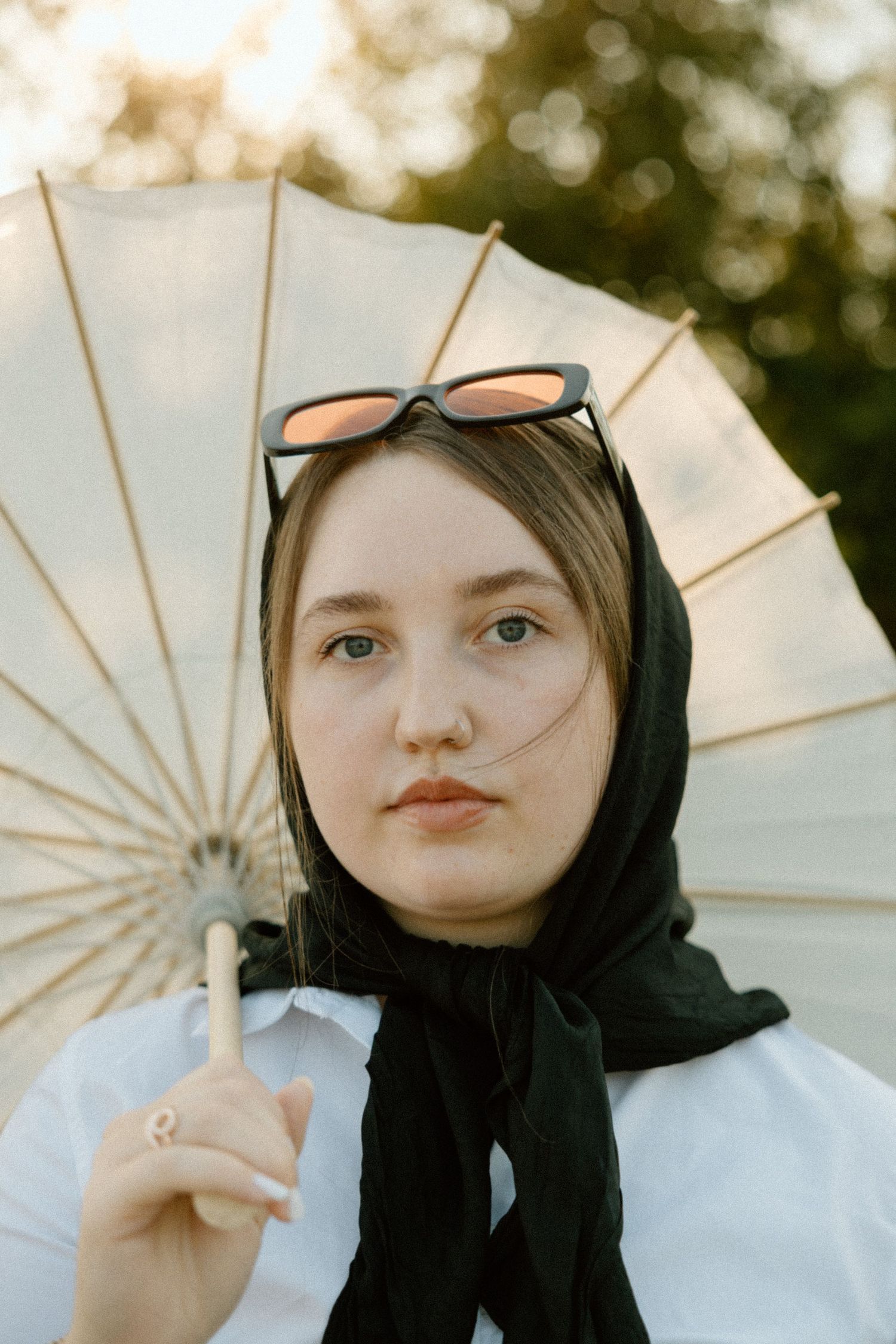 A series of artistic portraits with a white parasol and black headscarf in soft lighting.