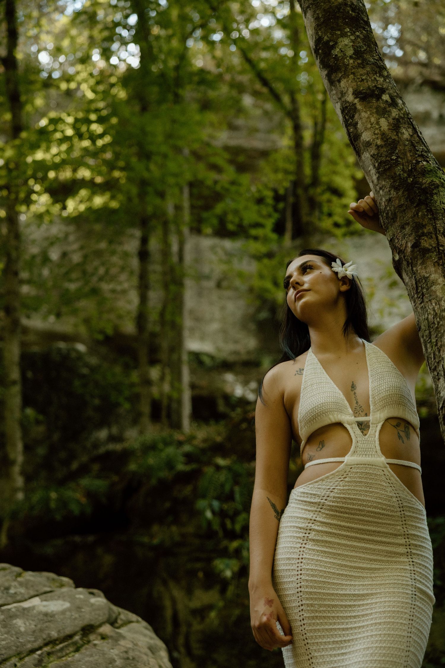Nature-inspired portrait sequence showing poses against a lush forest background with stone wall.
