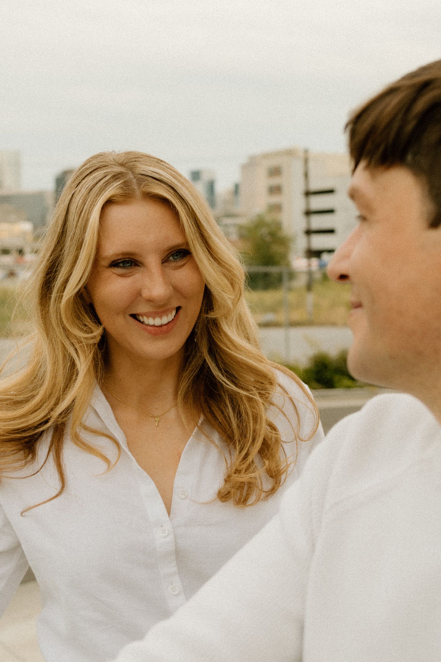 Couple in matching white outfits sharing a romantic moment on a rooftop.