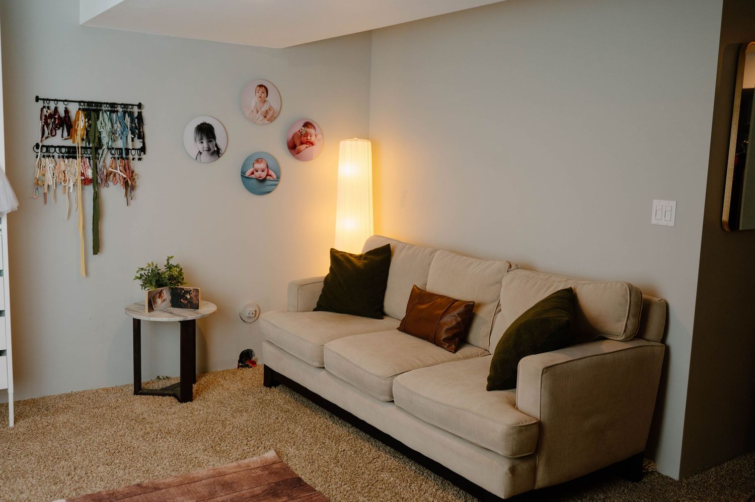 Cozy waiting area with beige sofa, warm floor lamp, decorative wall plates, and neutral carpet.