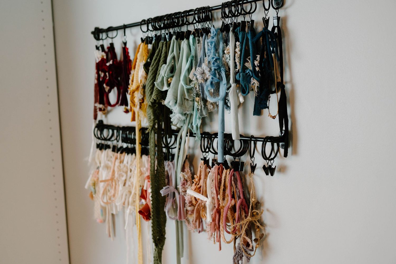 Colorful collection of newborn photography wraps and props organized on a decorative wall rack.
